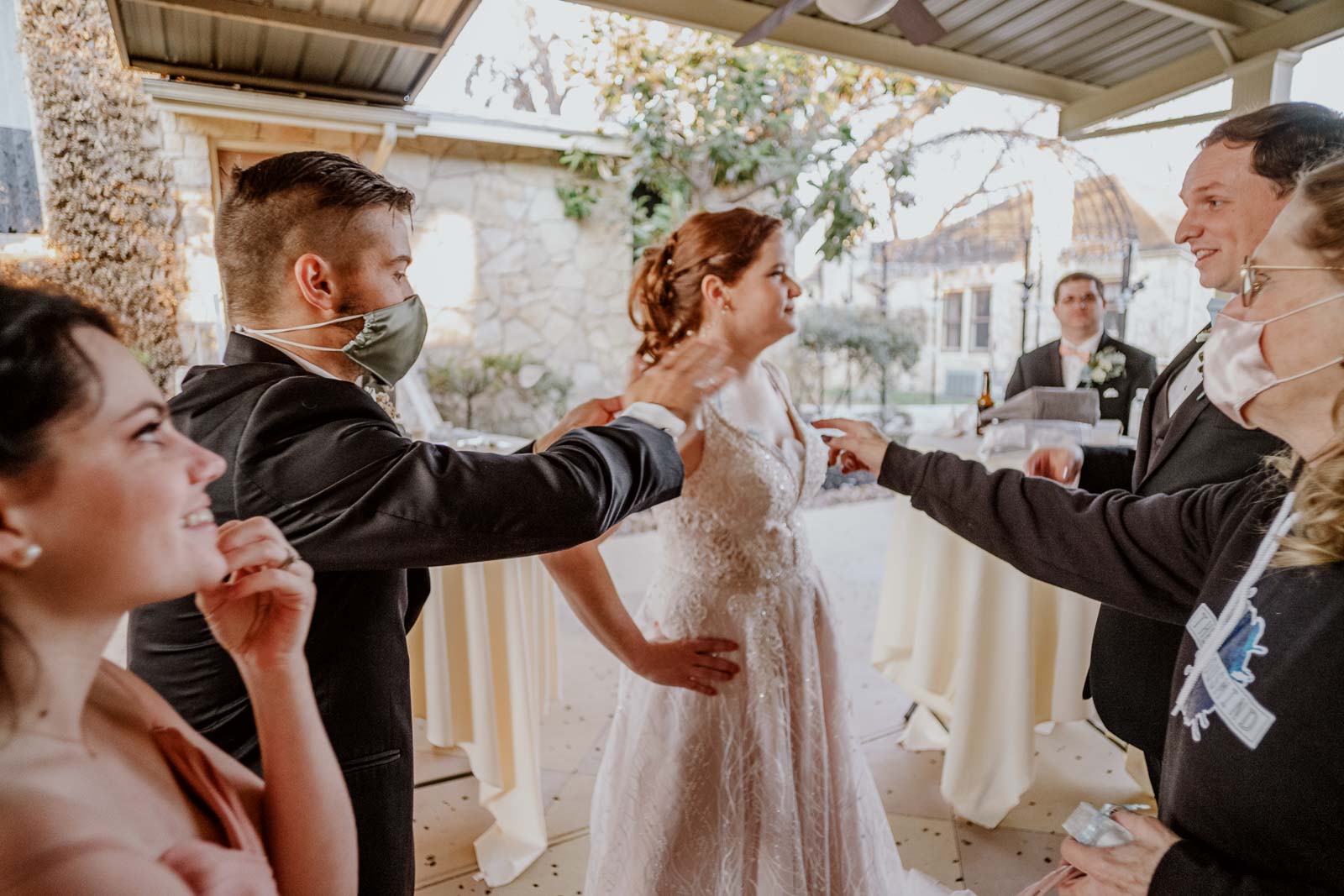 Family surround the bride with a bride hands on hips as petals are thrown at her and I hilarious moment