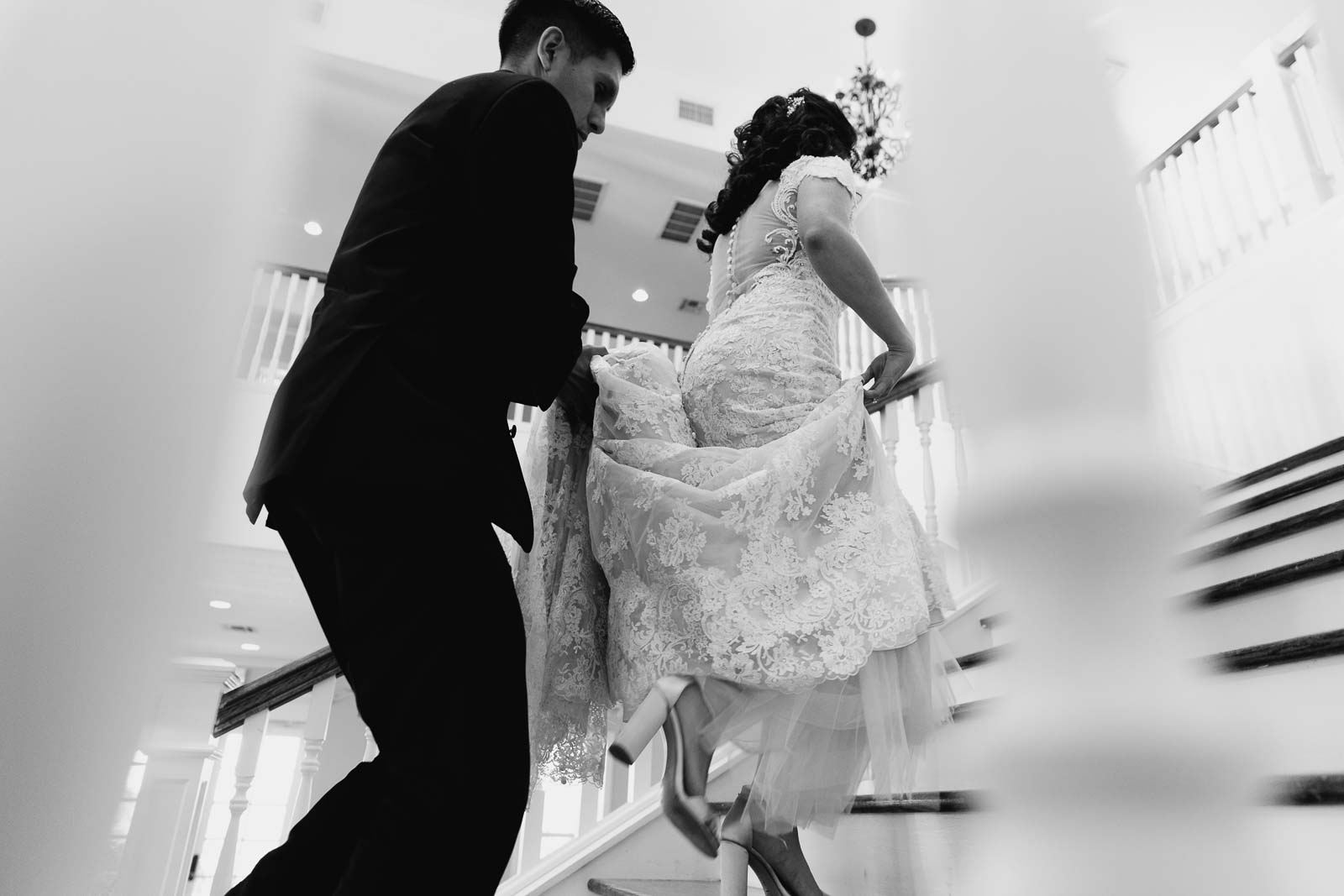 The groom clutches the bride‘s dress as she goes up the staircase at Kendall point low angle