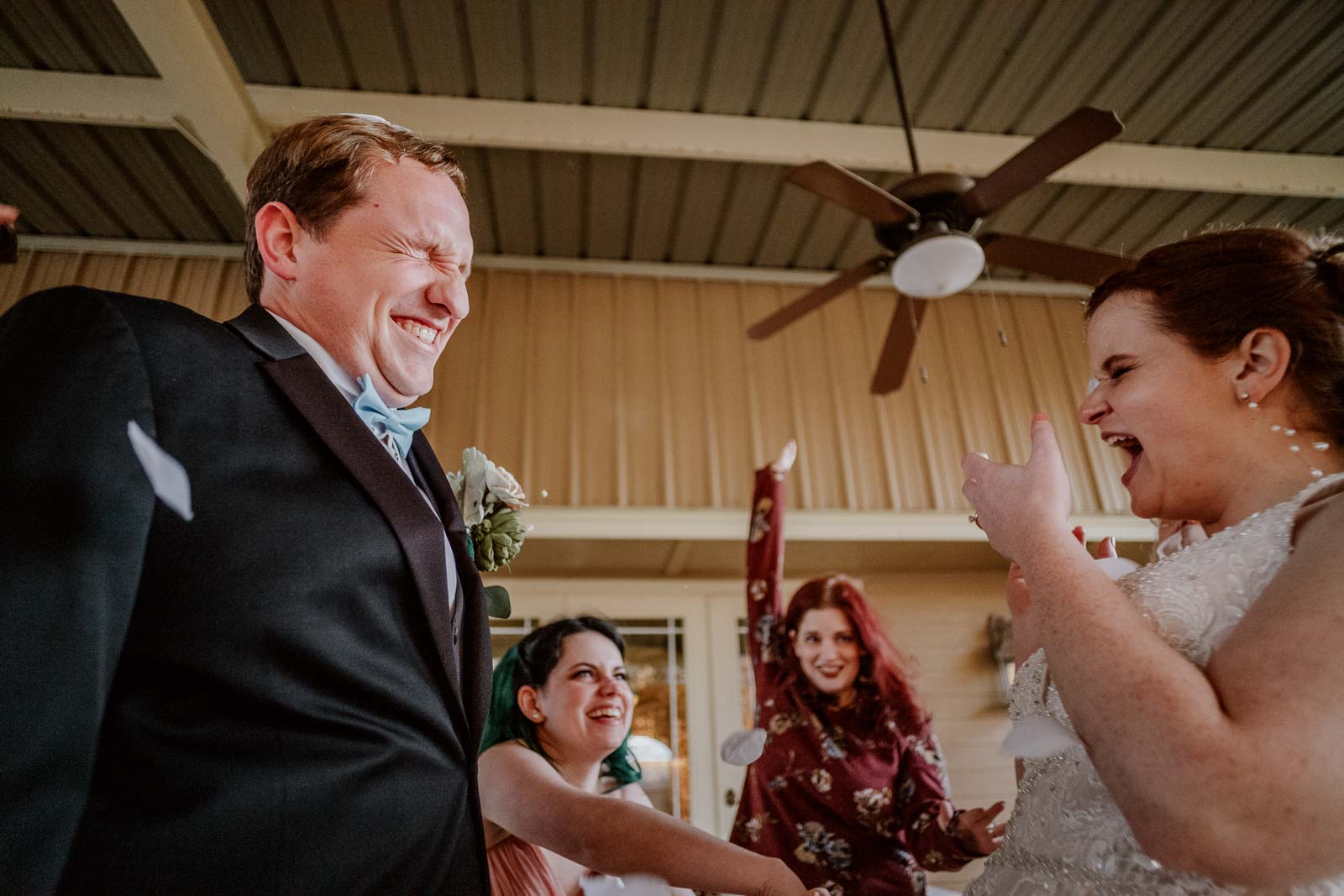 On their exit at Spinellis wedding venue a couple close our eyes as the sisters of the bride throw petals at the couple in a funny moment