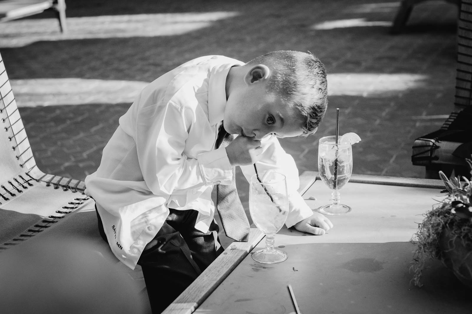 A little boy blows through his straw into the bottom of his glass on unaware of the camera