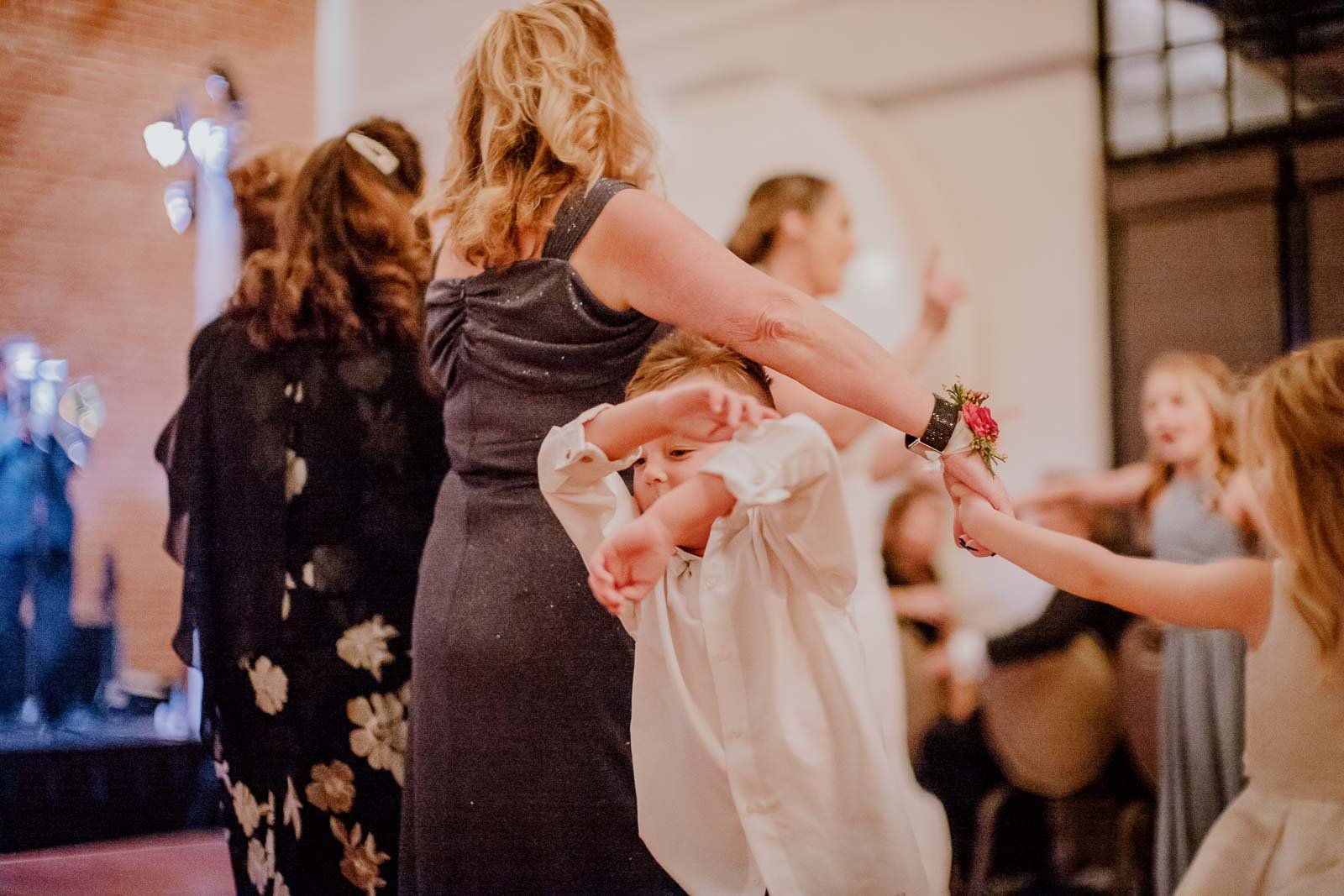 The ring bearer pushes his way through the crowd at a reception