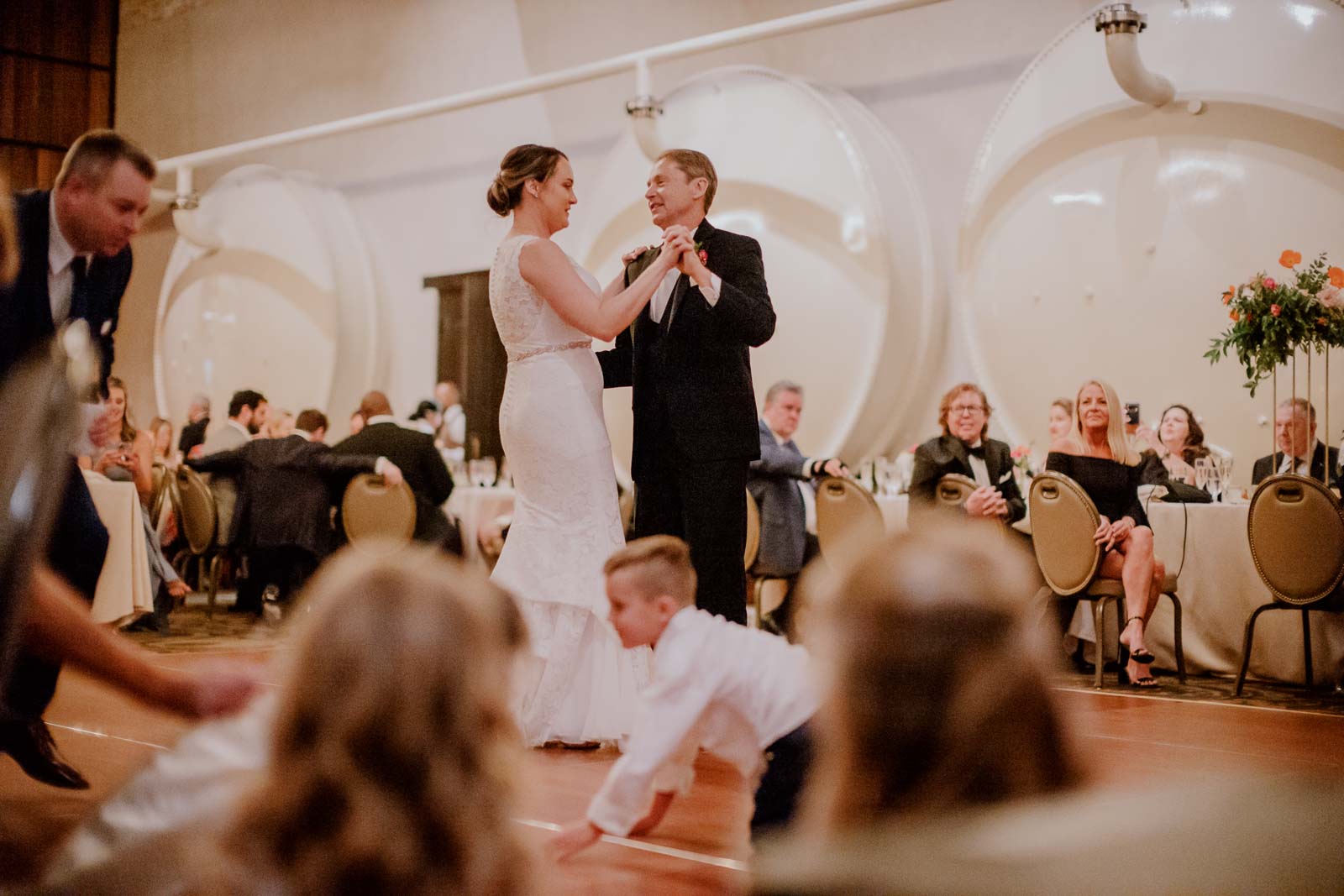 The father of the bride and the bride have the first dance in the elephant cellar at Hotel Emma as a ringbearer on his knees scurries away