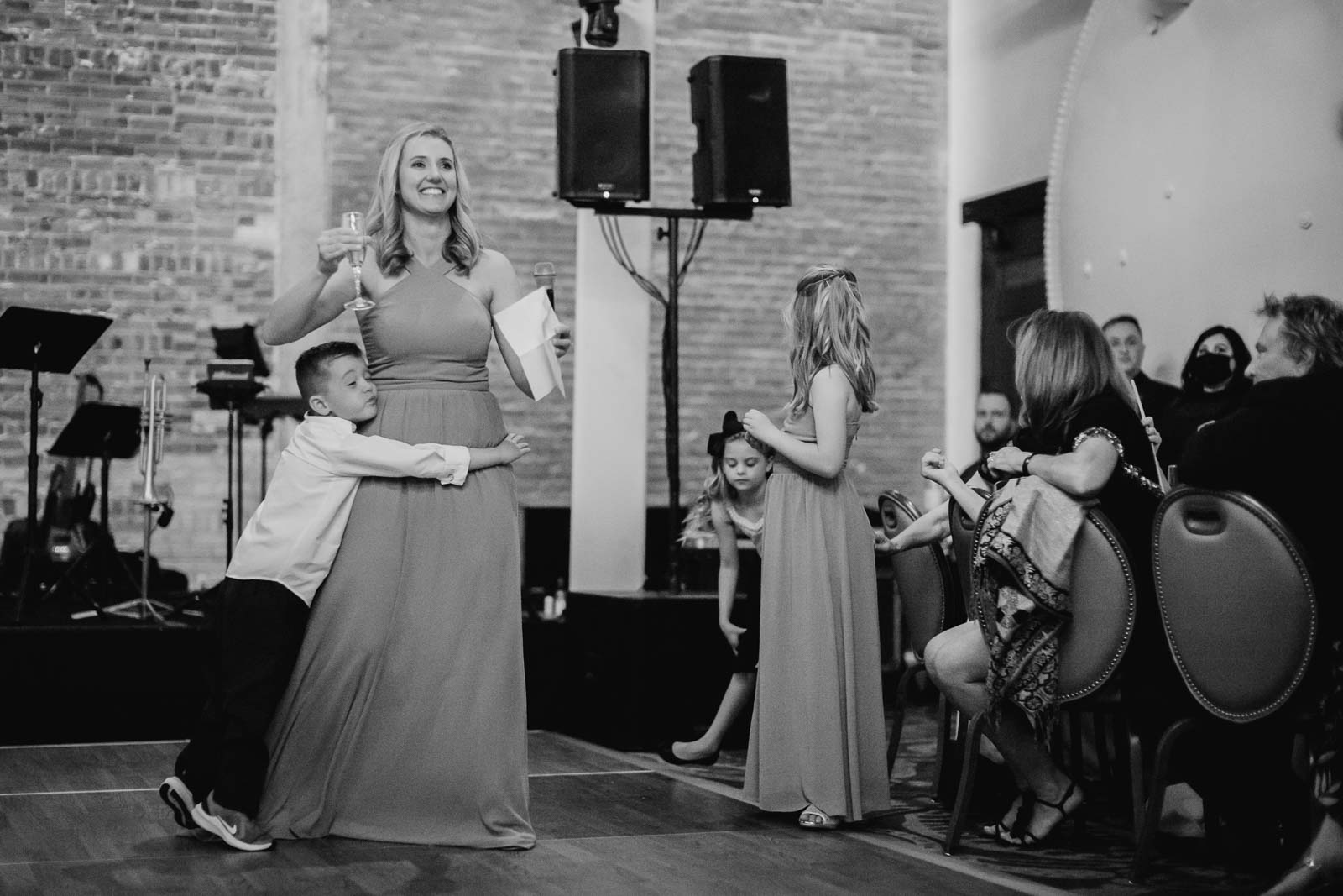 The sister of the bride makes her toast as her son hugs her