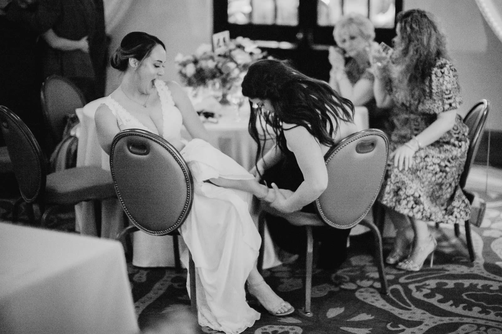 The bride has some help from a guest as she fixes and ties her shoe