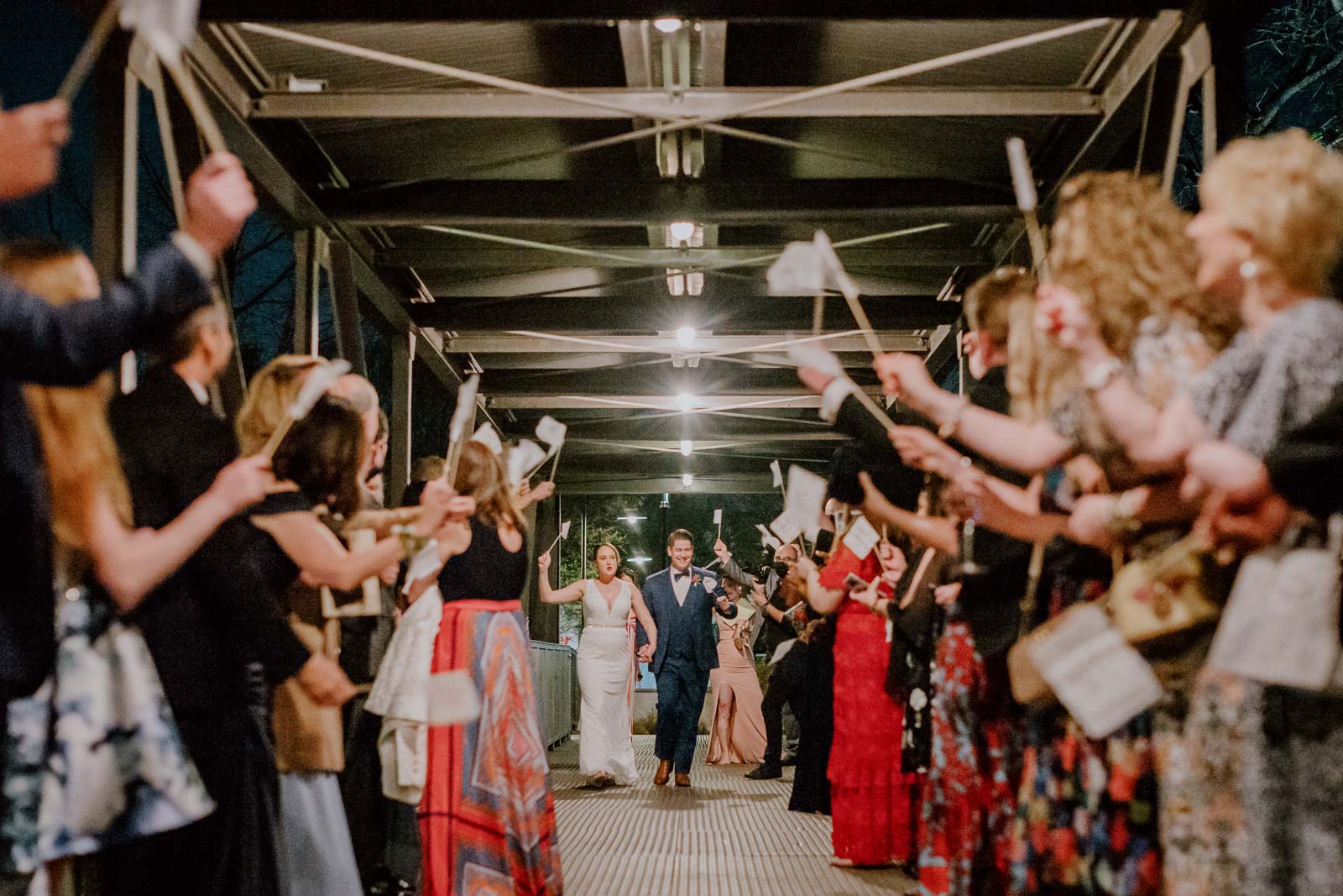 As friends share the bride and groom run towards the camera on their exit