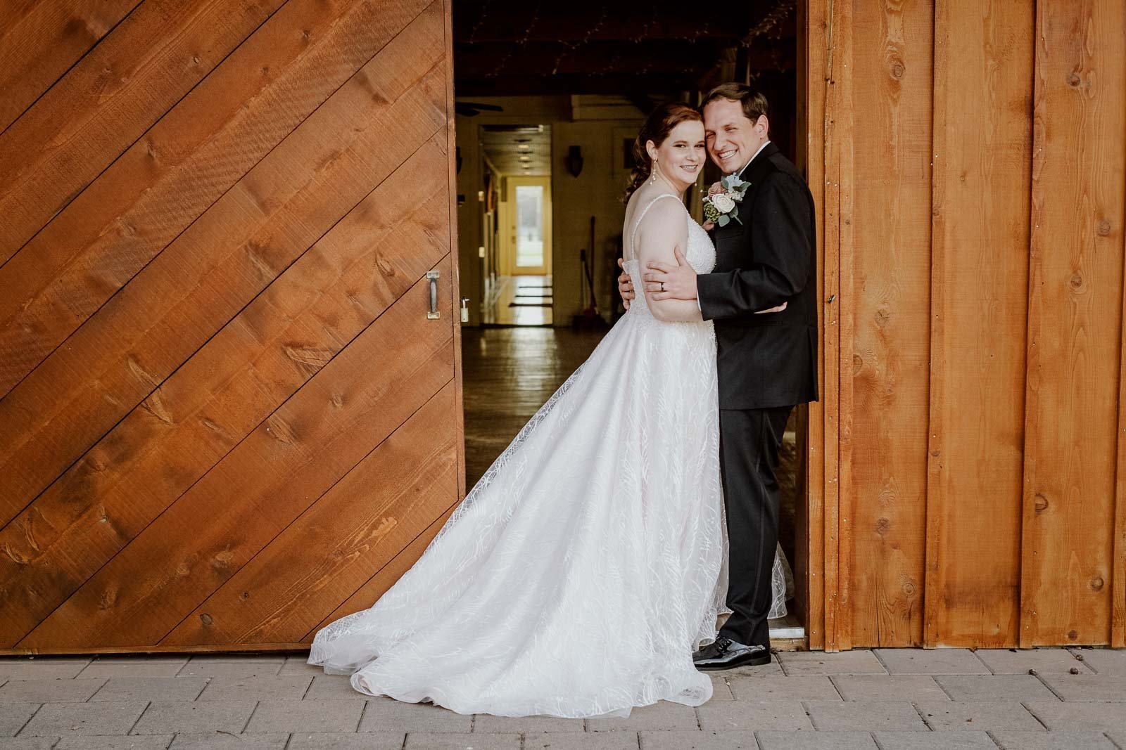 The couple pose for a photograph in the  barn doors at Spinelli