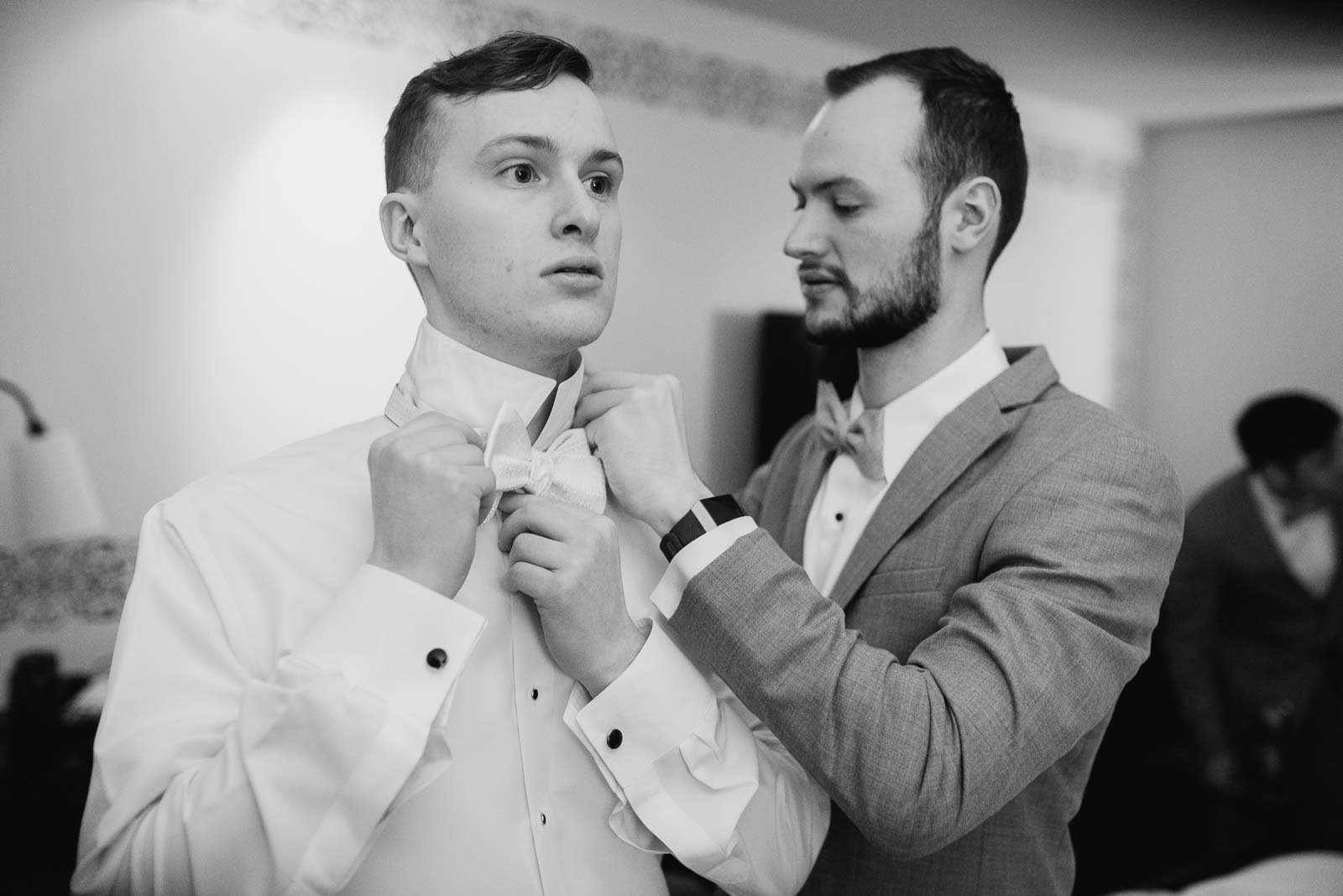 Daniel the groom is assisted by his brother putting on his bowtie at Hotel Valencia