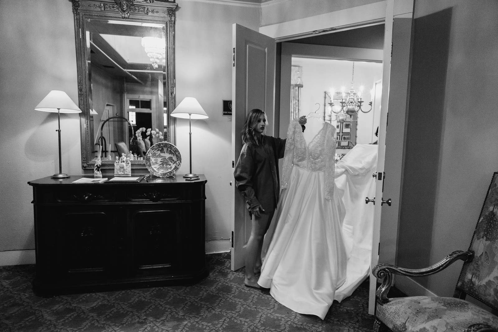 With help from the bridesmaids and they move the bridal dress from one room to the dressing room