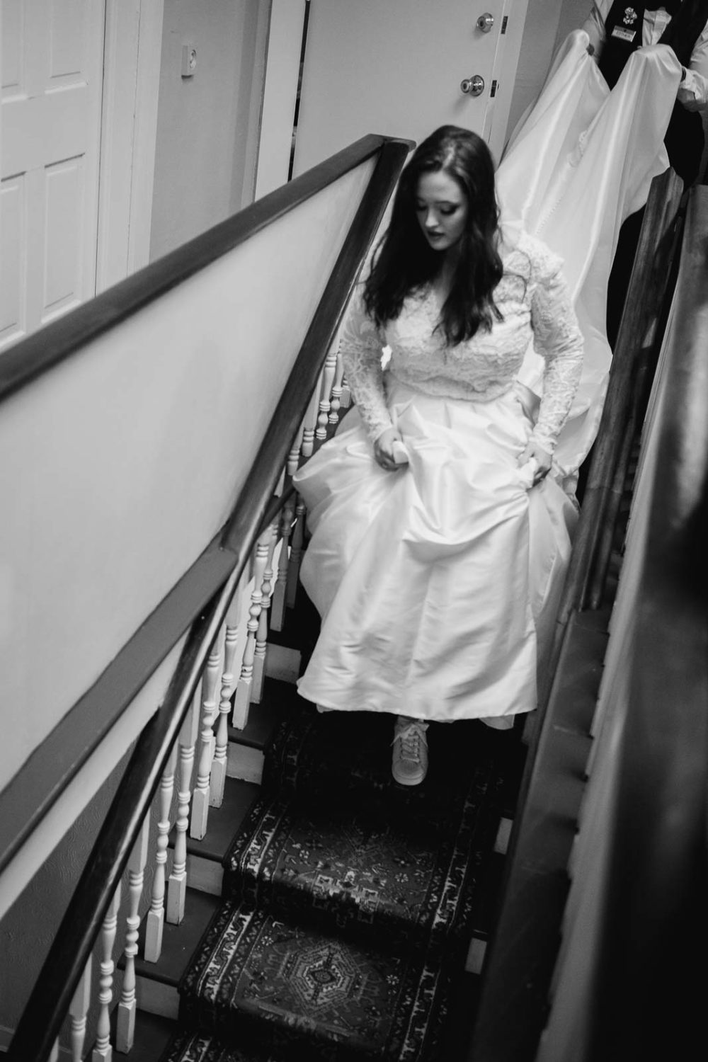 The bride makes her way down a narrow staircase 