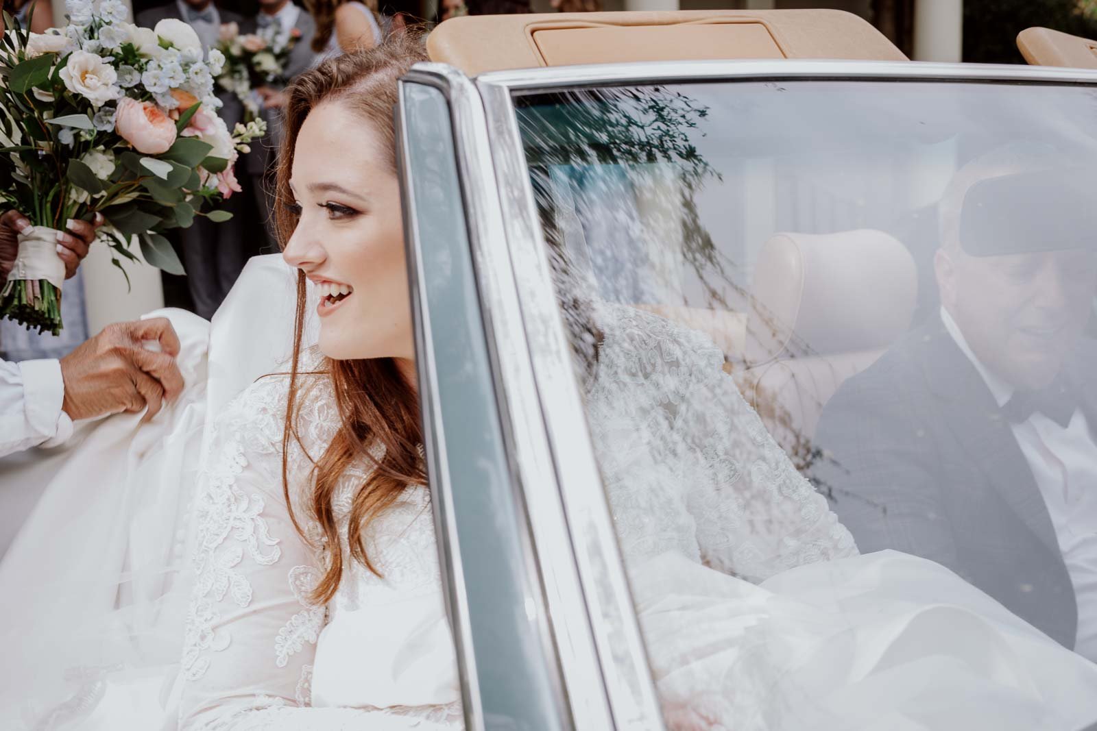 The bride enters a beautiful antique car to drive her to the ceremony spot by her uncle