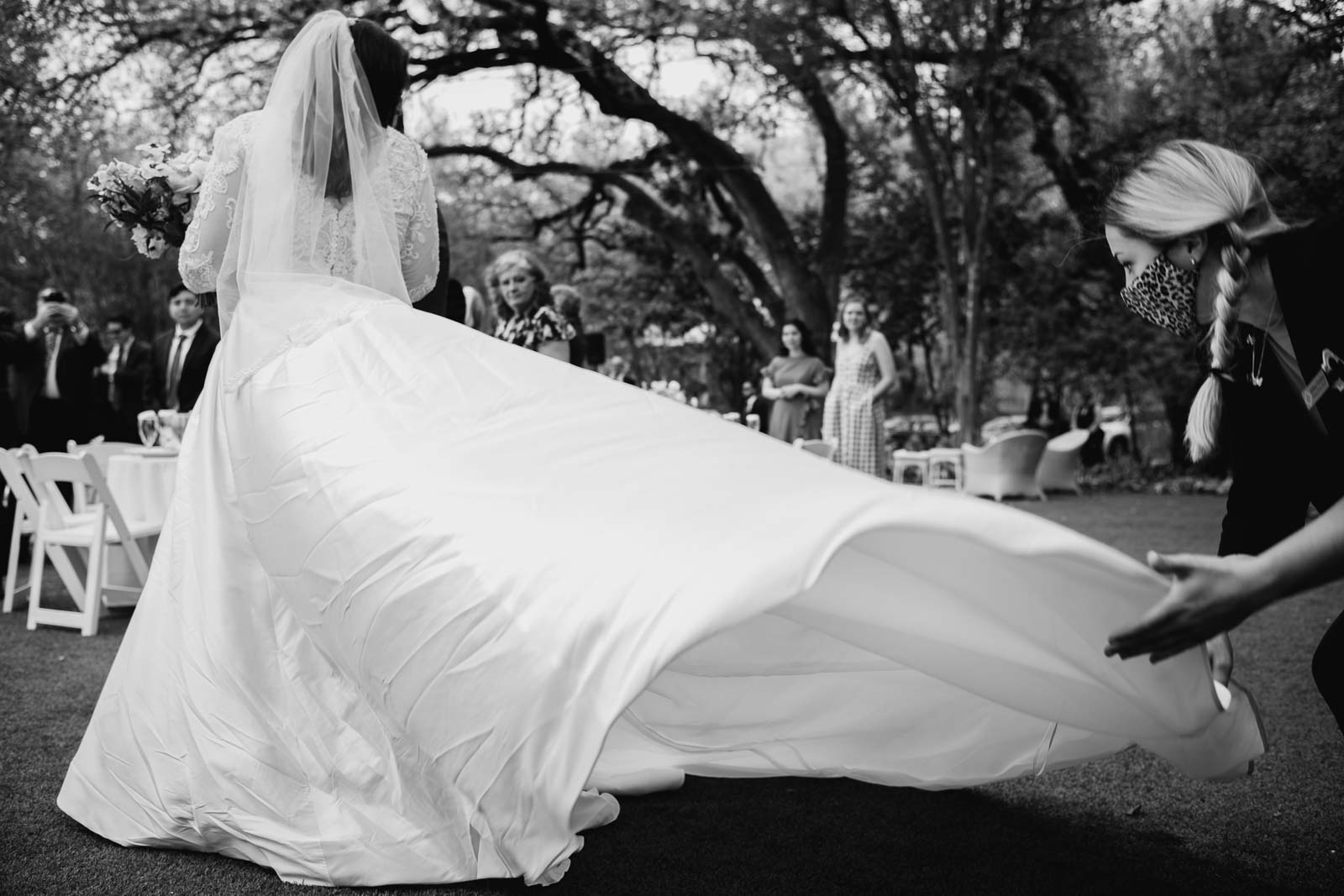 As a bride enters the center aisle the wedding planners assistant straightens the brides dress