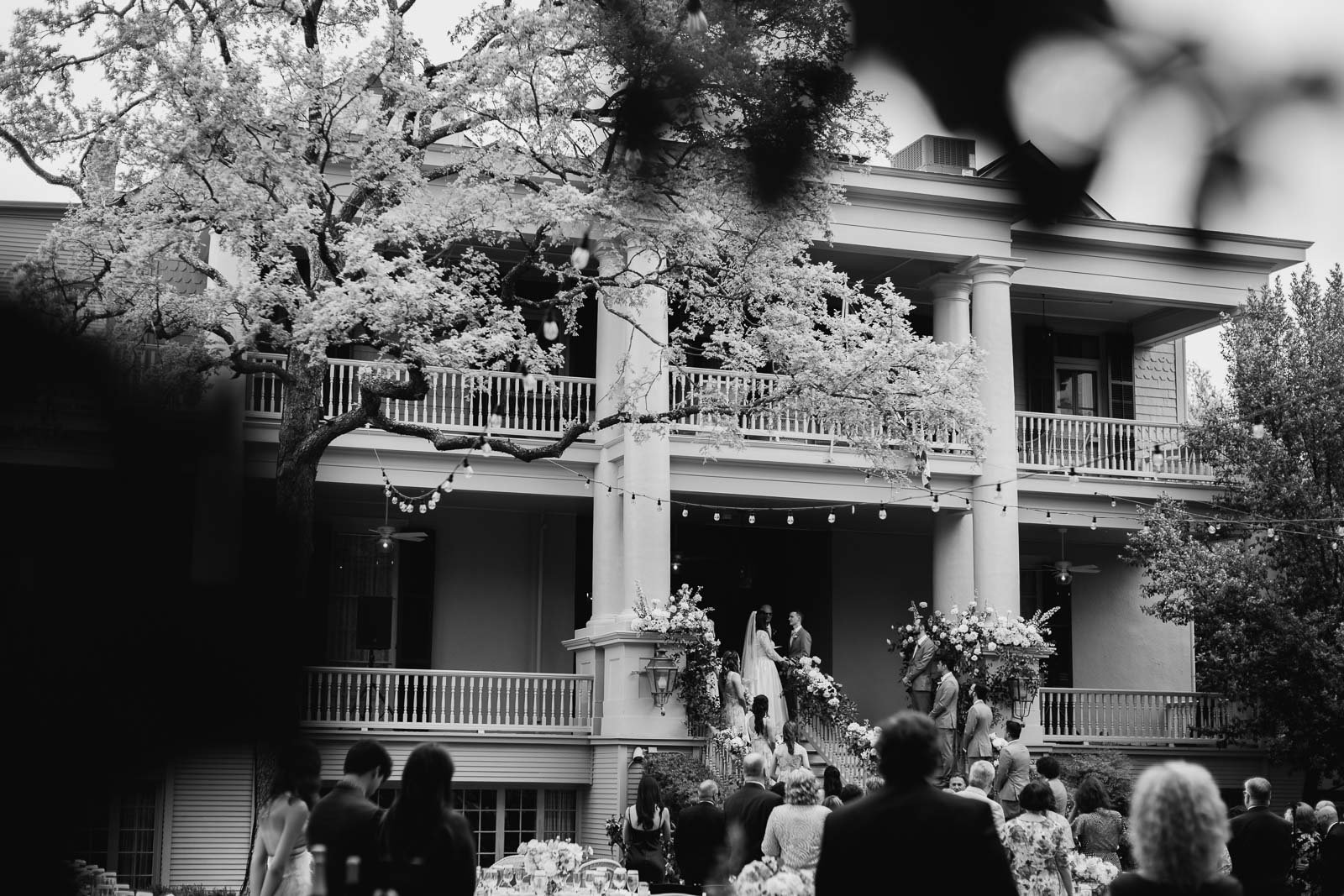 A wide angle view in monochrome photograph from the back of the ceremony looking towards The Argyle as a bride and groom