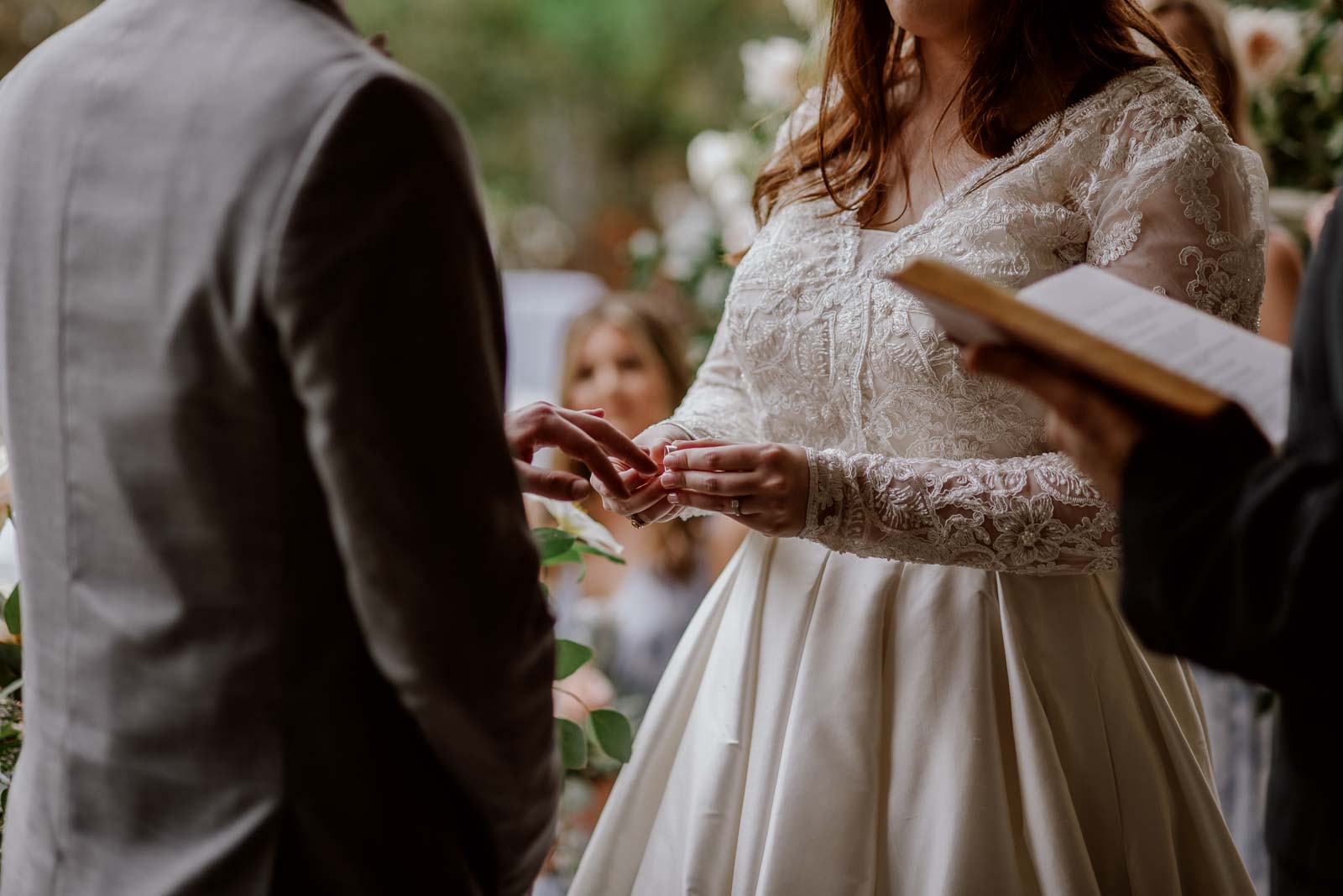 A bride places a ring on the grooms finger in a close-up shot