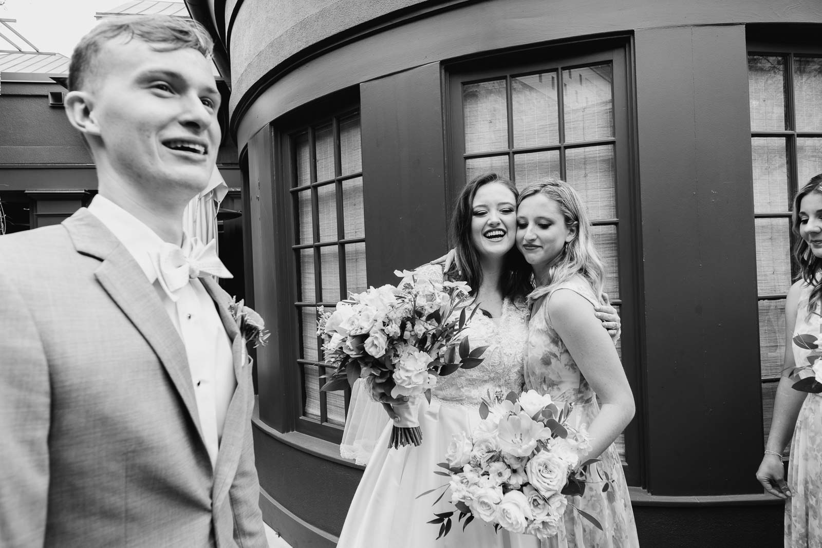 The wedding party celebrates as sisters hug