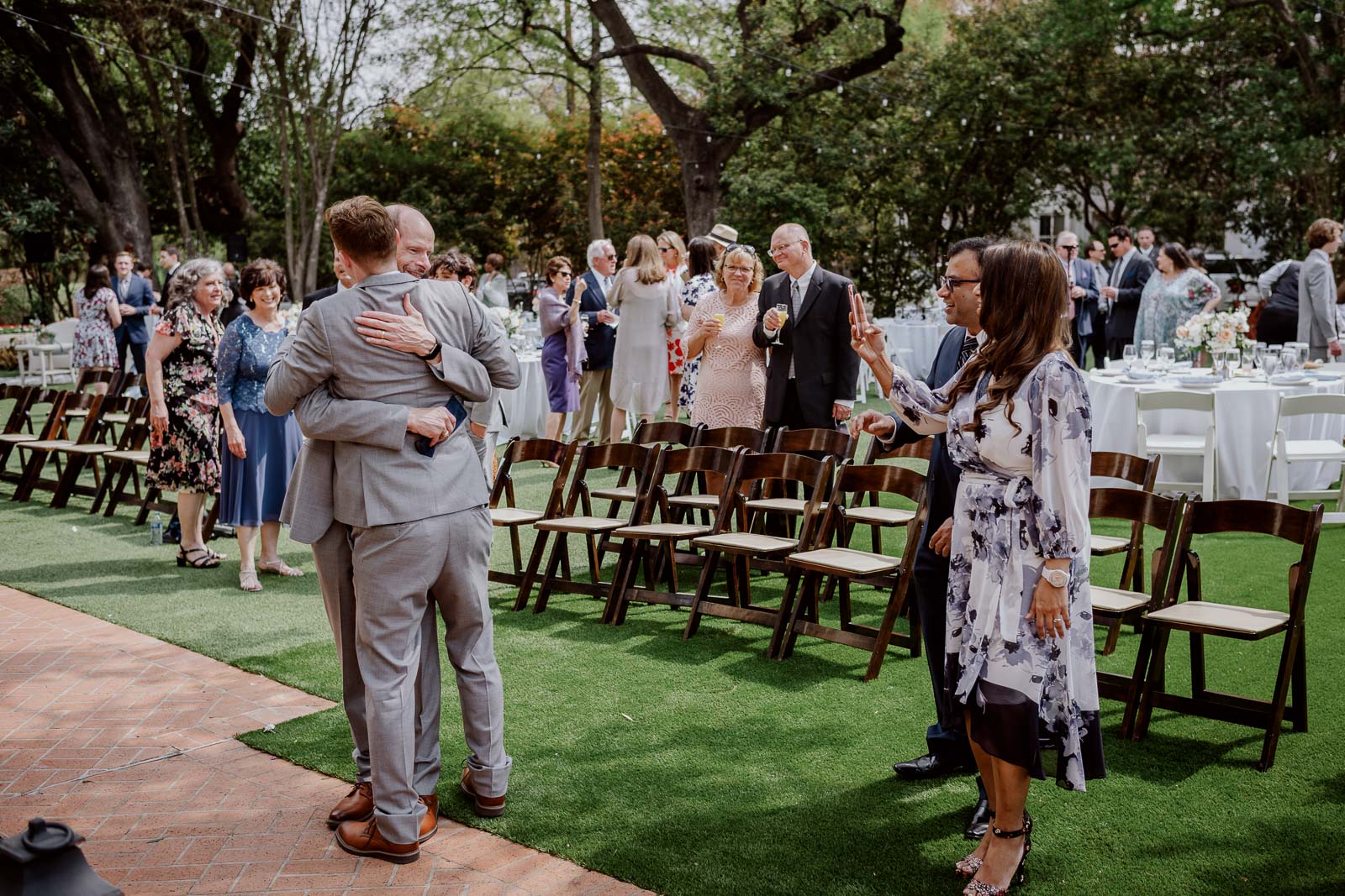 A photograph of the father and son hugging as a  wedding guest snaps a photograph of them