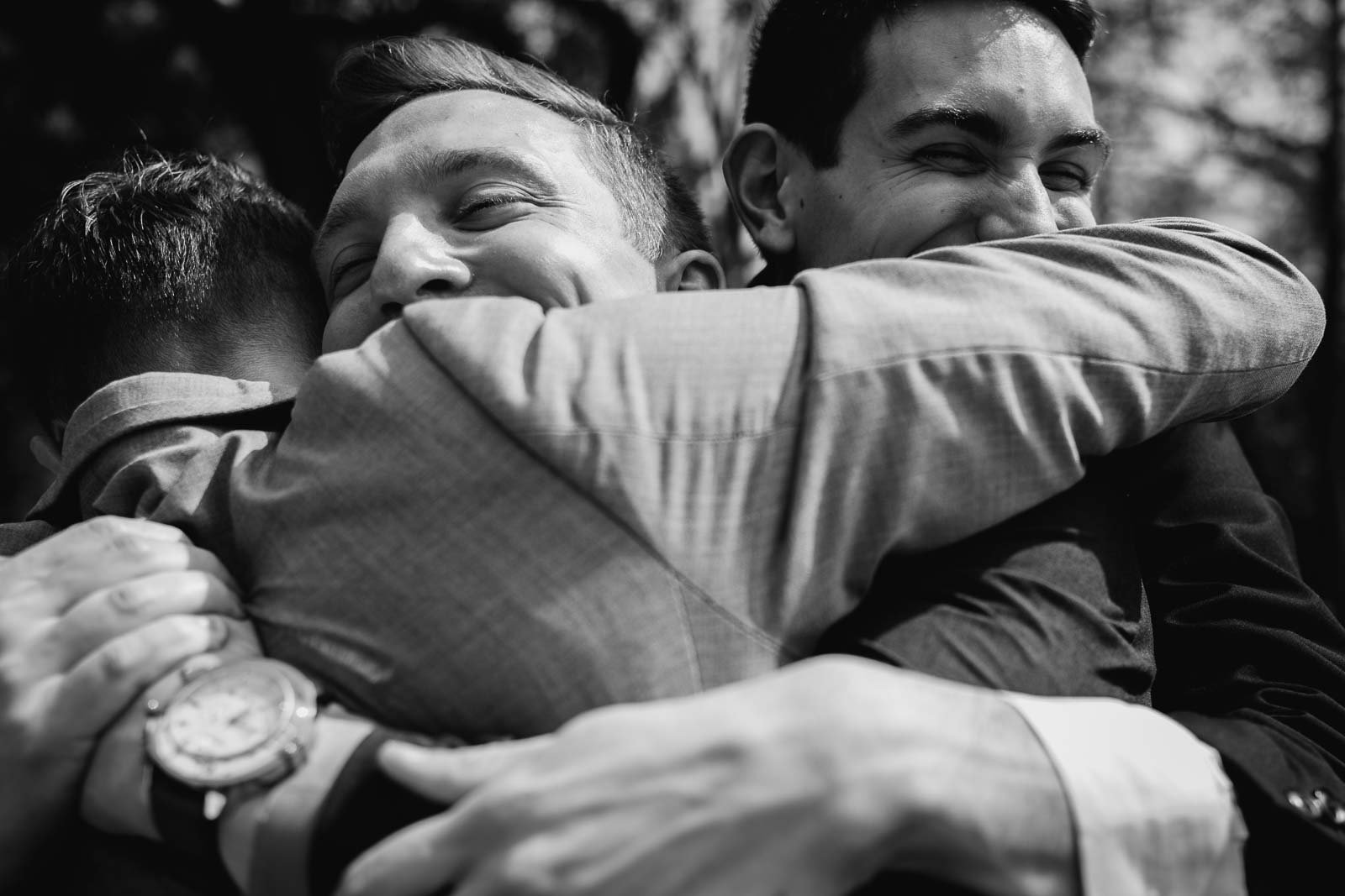 A wide angle close-up shot of friends of the groom hugging deliriously so happy