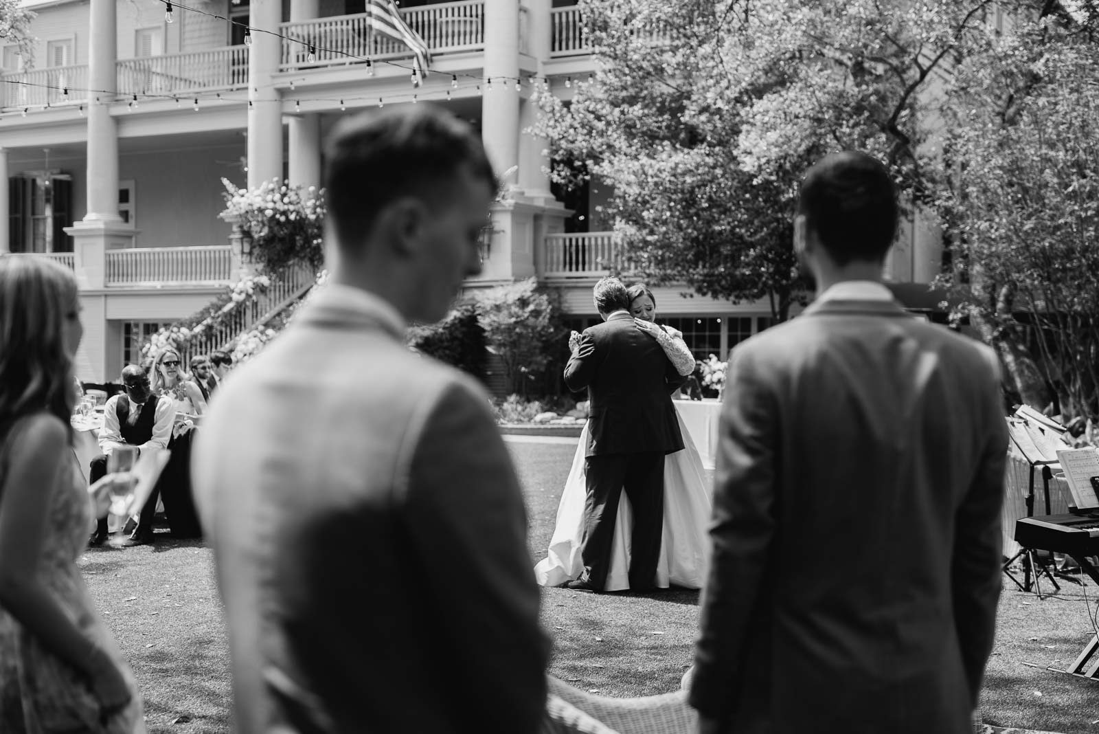 Photograph from behind the groom and groomsmen a look on as the father of the bride and the bride had the first father daughter dance