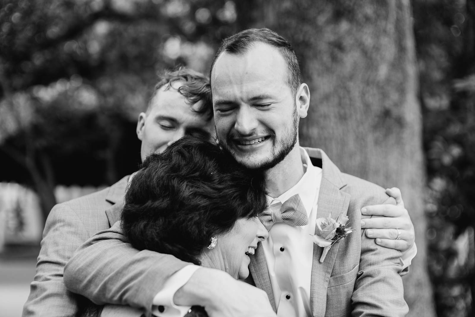 The brother of the groom hugs his mother as a cry and joy