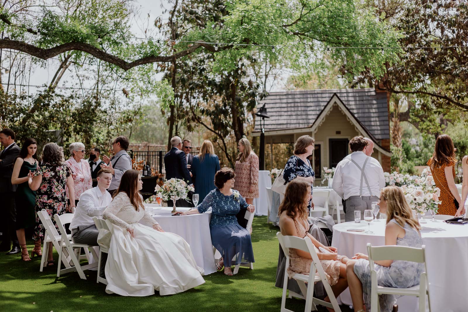 During the spring reception the photo shows guests mingling with the bride and groom sitting on the outside lawn chairs