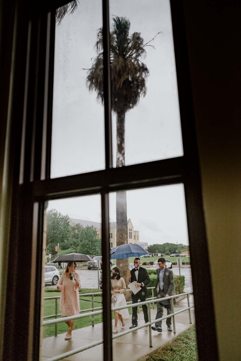 The groom arrives with palm tree in background photographed through window at Sacred Heart Chapel-Leica photographer-Philip Thomas Photography