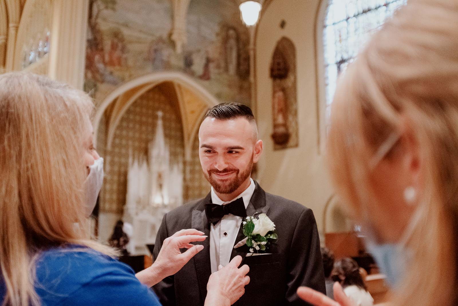 A flower is placed on grooms lapel at wedding ceremony Sacred Heart Chapel-Leica photographer-Philip Thomas Photography