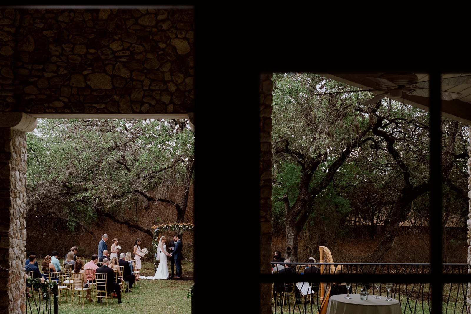 A photograph taken from the main building of the veranda during the ceremony looking out on the lawn with the hope is in the right and the couple in the middle