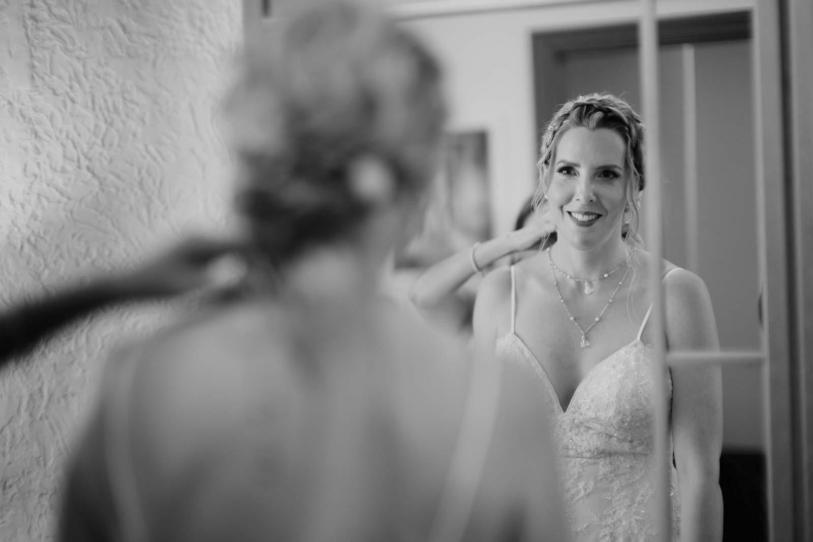 A close-up shot of the bride ashy changes into a second dress on her wedding day looking in the mirror very happy
