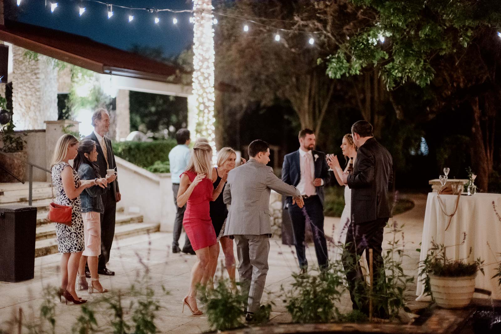 Reception guests dance at the veranda under available light photographed by Leica documentary photographer Philip Thomas