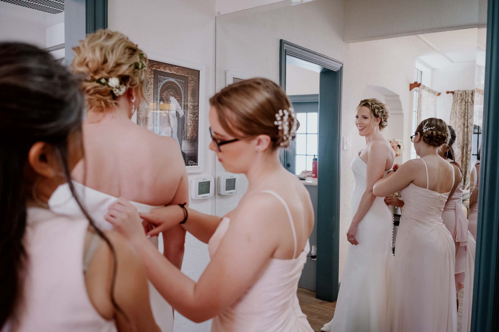As the bride dresses on her wedding day her daughter helps tie the back of her dress