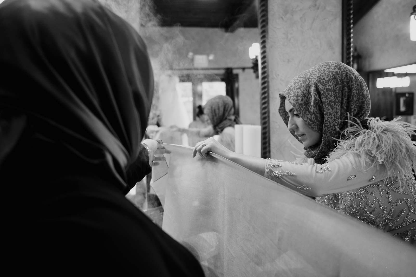 Friends and family of the bride steam the veil