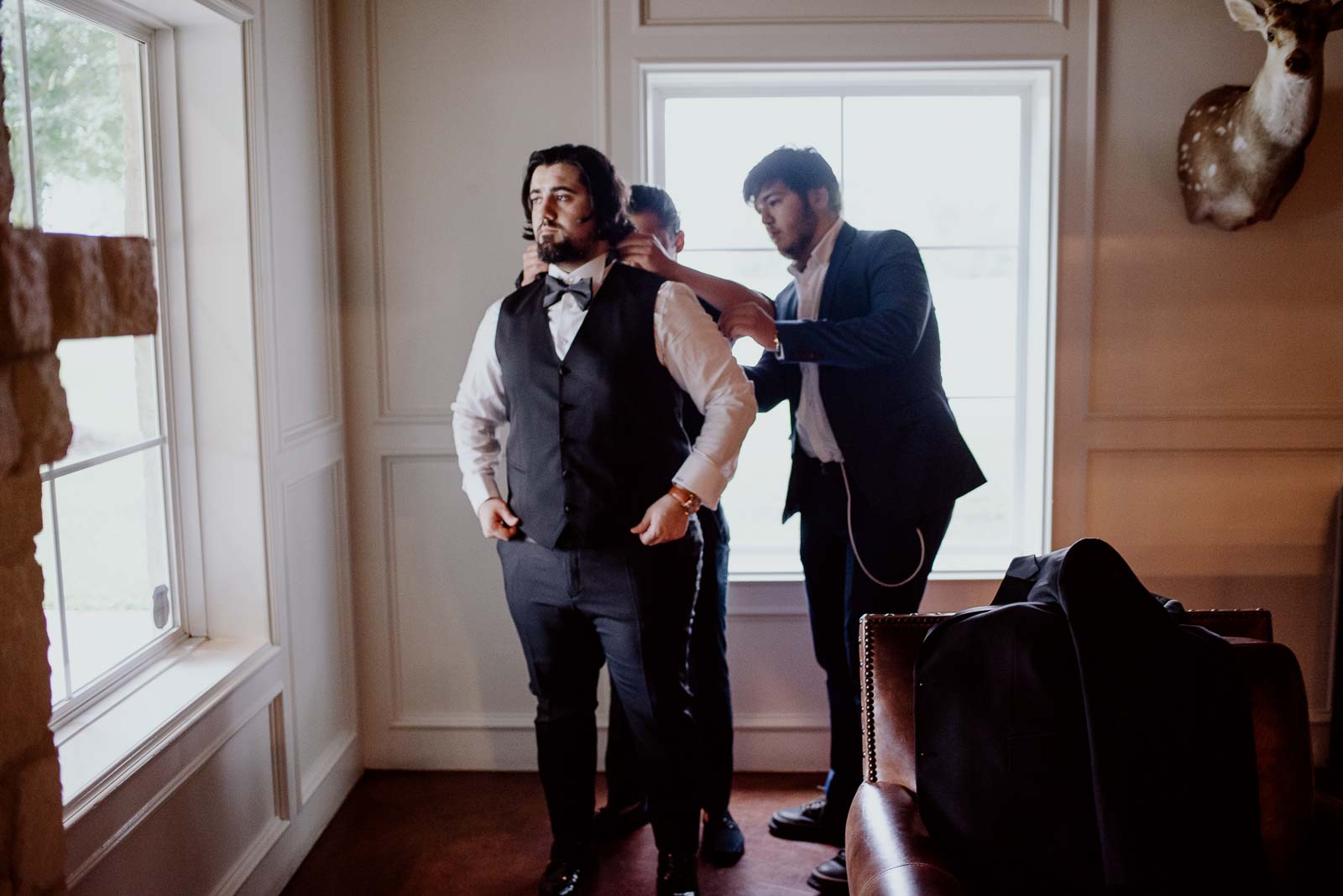 The groom has his shirt and collar fitted by family friends man