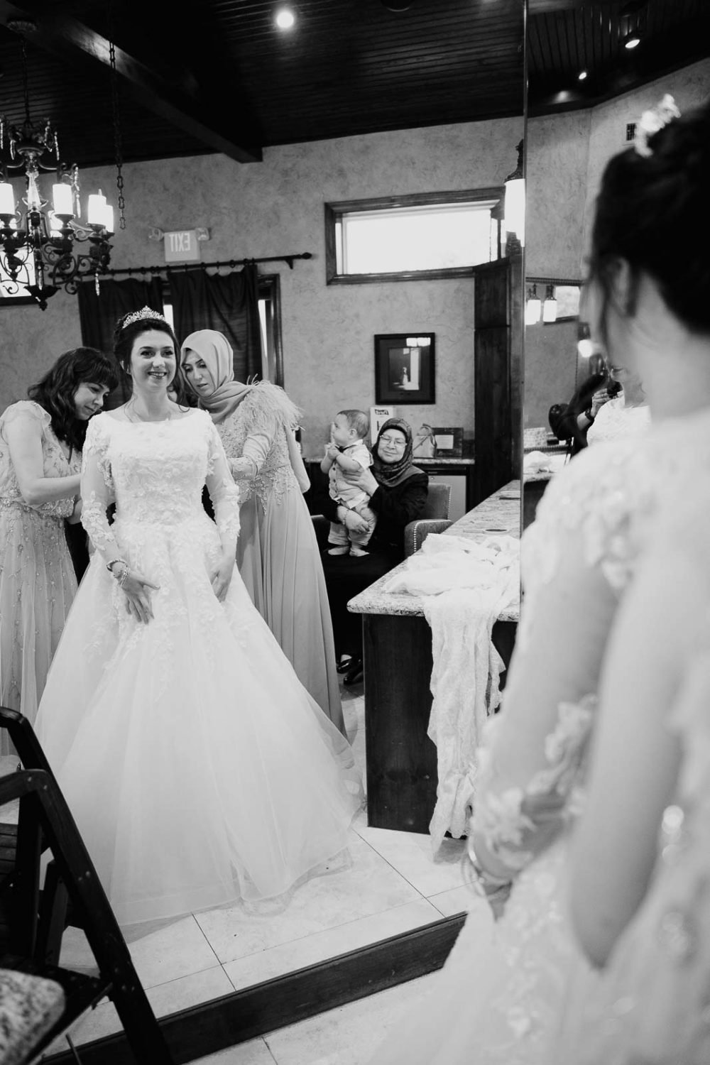 Bride looks in the mirror as final touches a completed to her dress at a Turkish wedding
