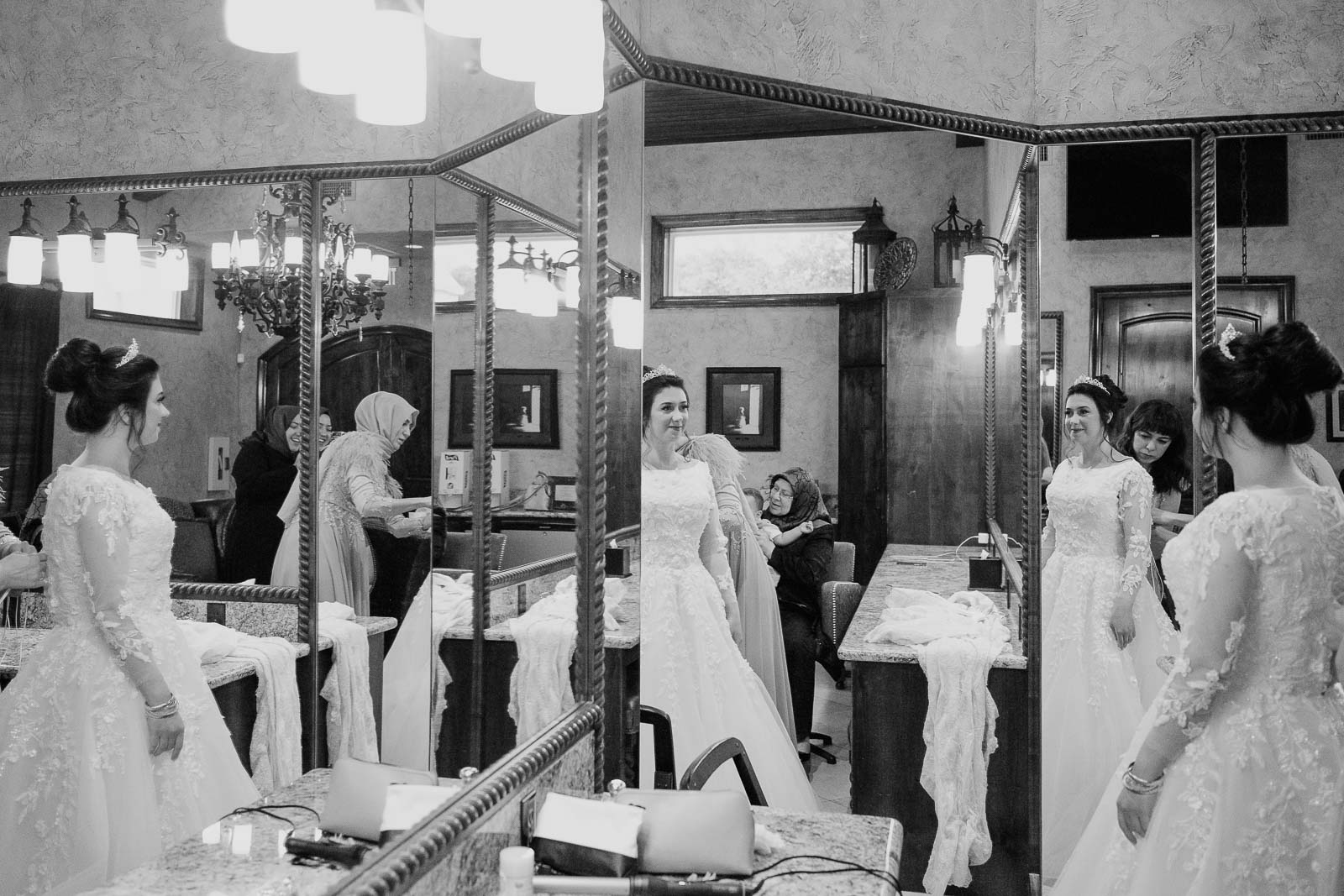 In a multiple mirrors  the Bride checks her self as final touches are applied