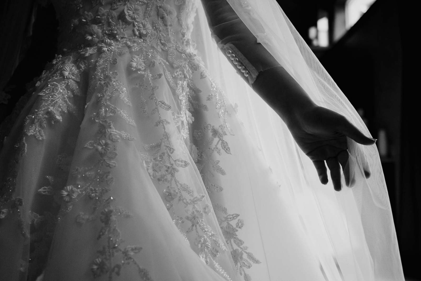 Hand of the brand of the bride silhouettes against her dress
