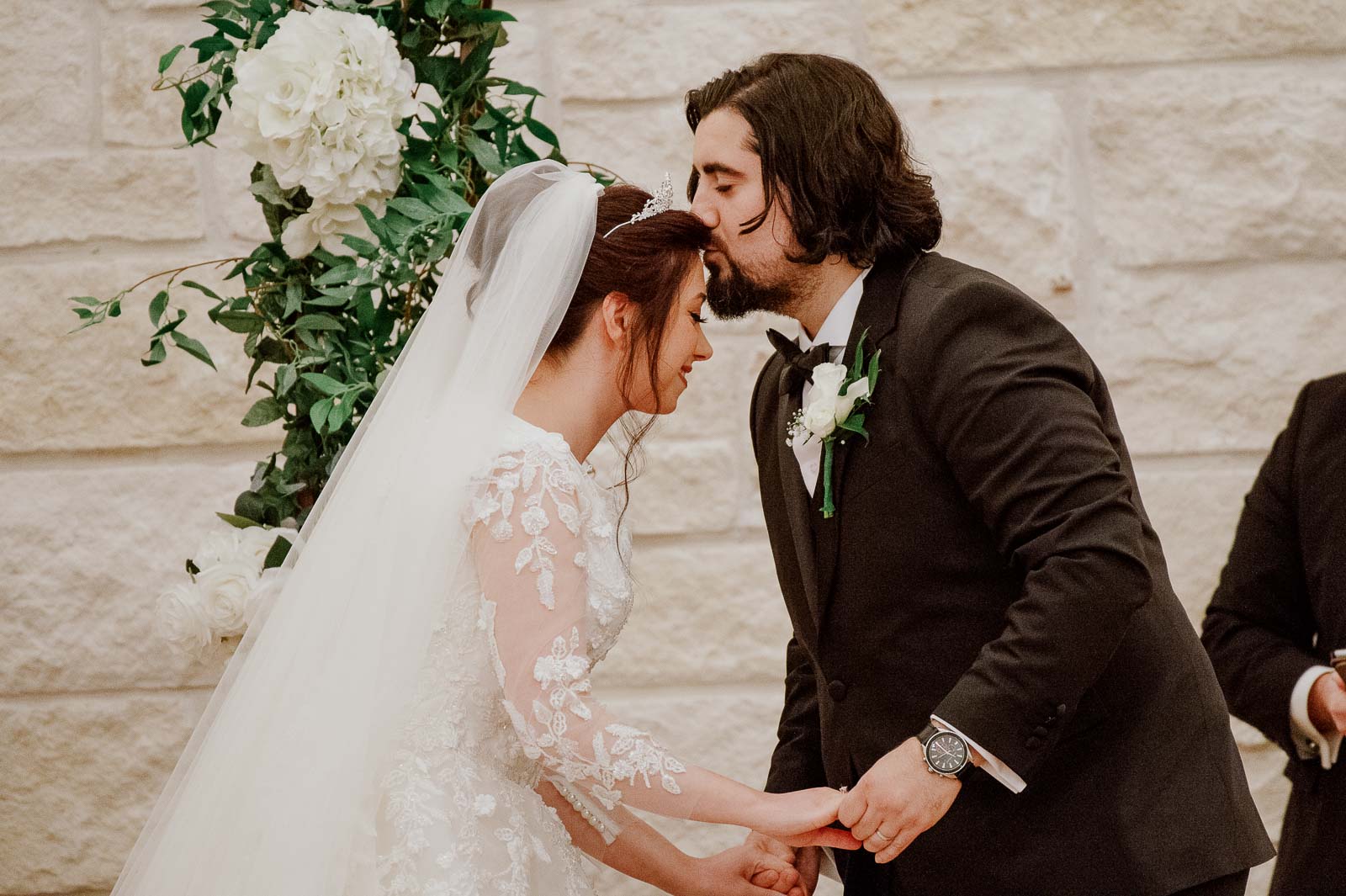 The groom kisses for head of the bride during the ceremony