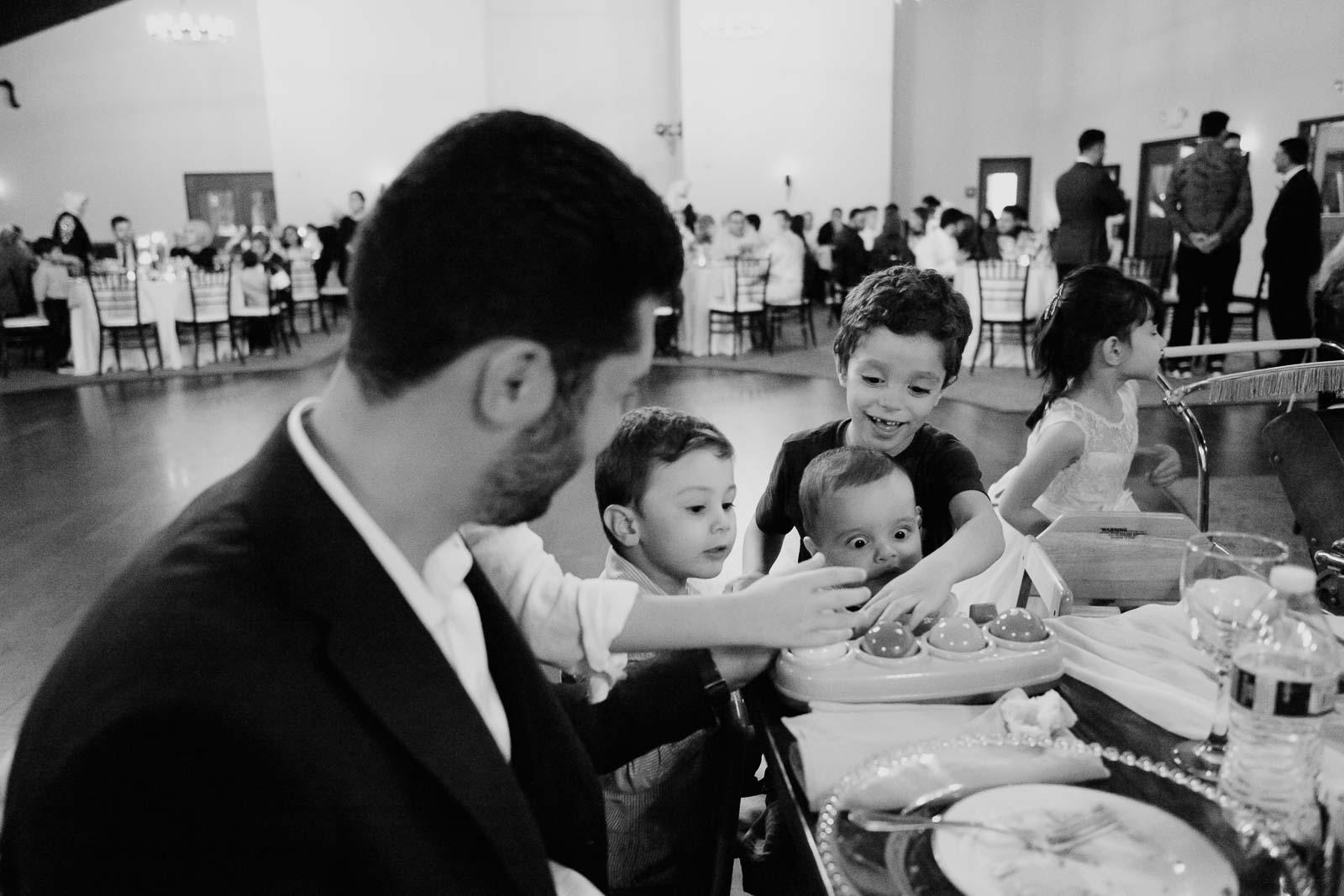 A baby at a table spread by family and friends play the toy