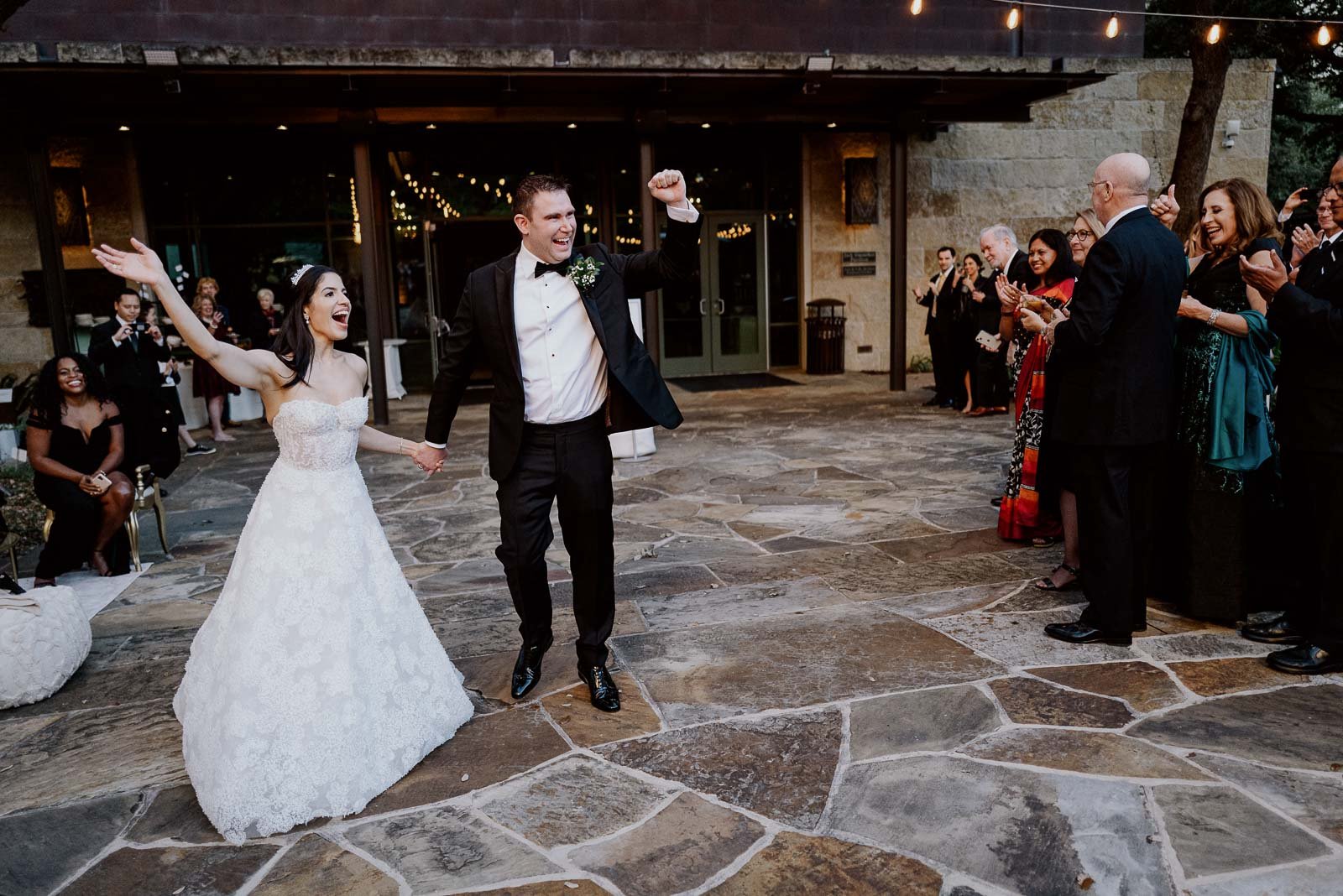 A newly married couple jubiantly raise their hands entering the Jack Guenther Pavilion at Briscoe Western Art Museum Wedding Receptionding Texas Leica Wedding Photographer Philip Thomas
