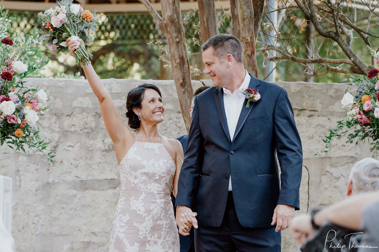 Just newly minted couple bride raises her bouquet in delight Club Giraud Wedding Reception San Antonio weddings Philip Thomas Photography