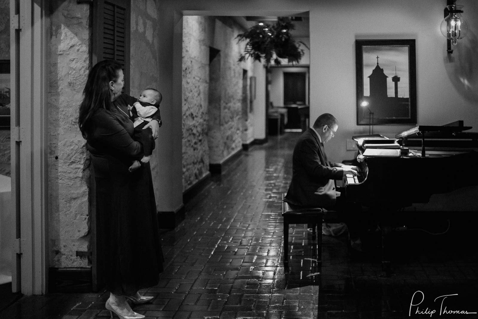 A baby is held tightly with piano player in background Club Giraud Wedding Reception San Antonio weddings Philip Thomas Photography