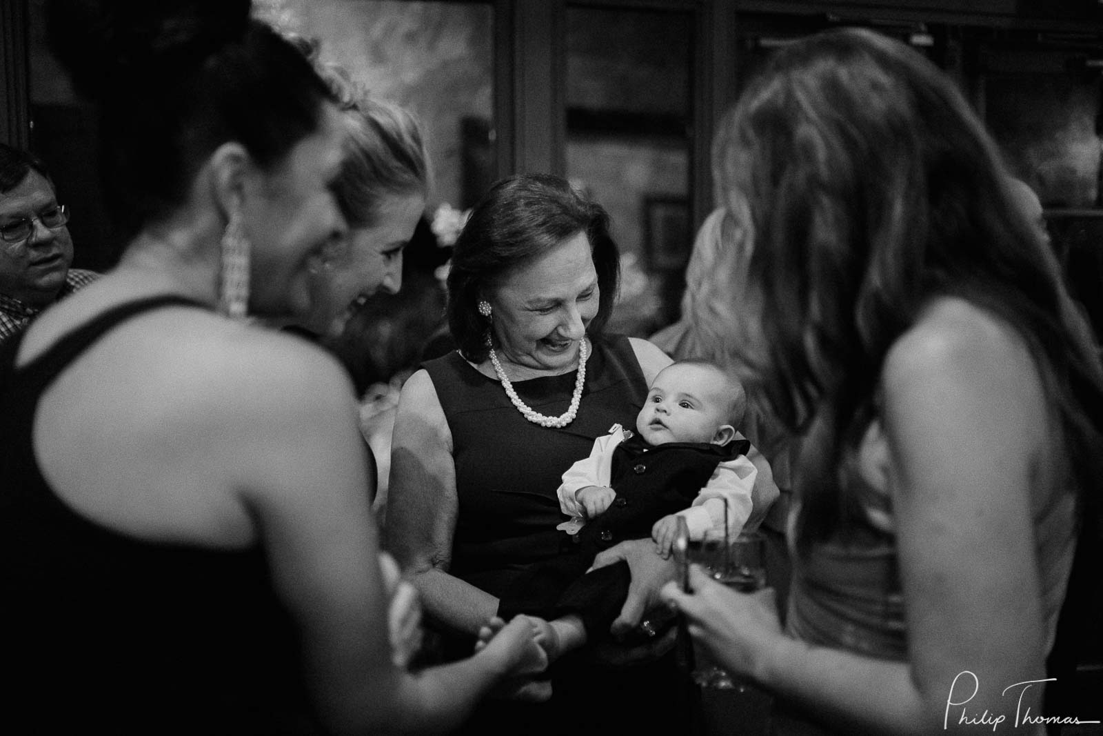 A grandmother holds her baby proudly surrounded by family and friends at Club Giraud Wedding Reception San Antonio weddings Philip Thomas Photography