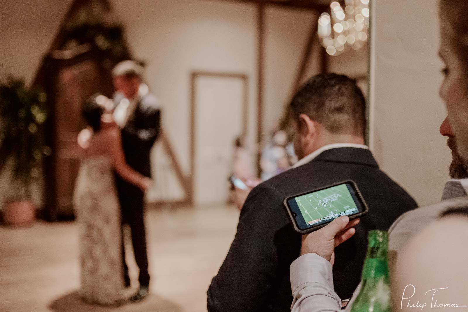 During first dance a guest plays a football game on her phone - Club Giraud Wedding Reception San Antonio weddings Philip Thomas Photography