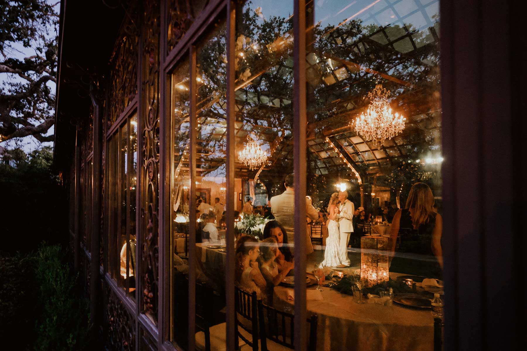 A San Antonio Wedding reception first dance father and daughter at dusk captured through conservatory window surrounded by reception guests - wedding photo by Philip Thomas is a San Antonio wedding photographer L1000635b