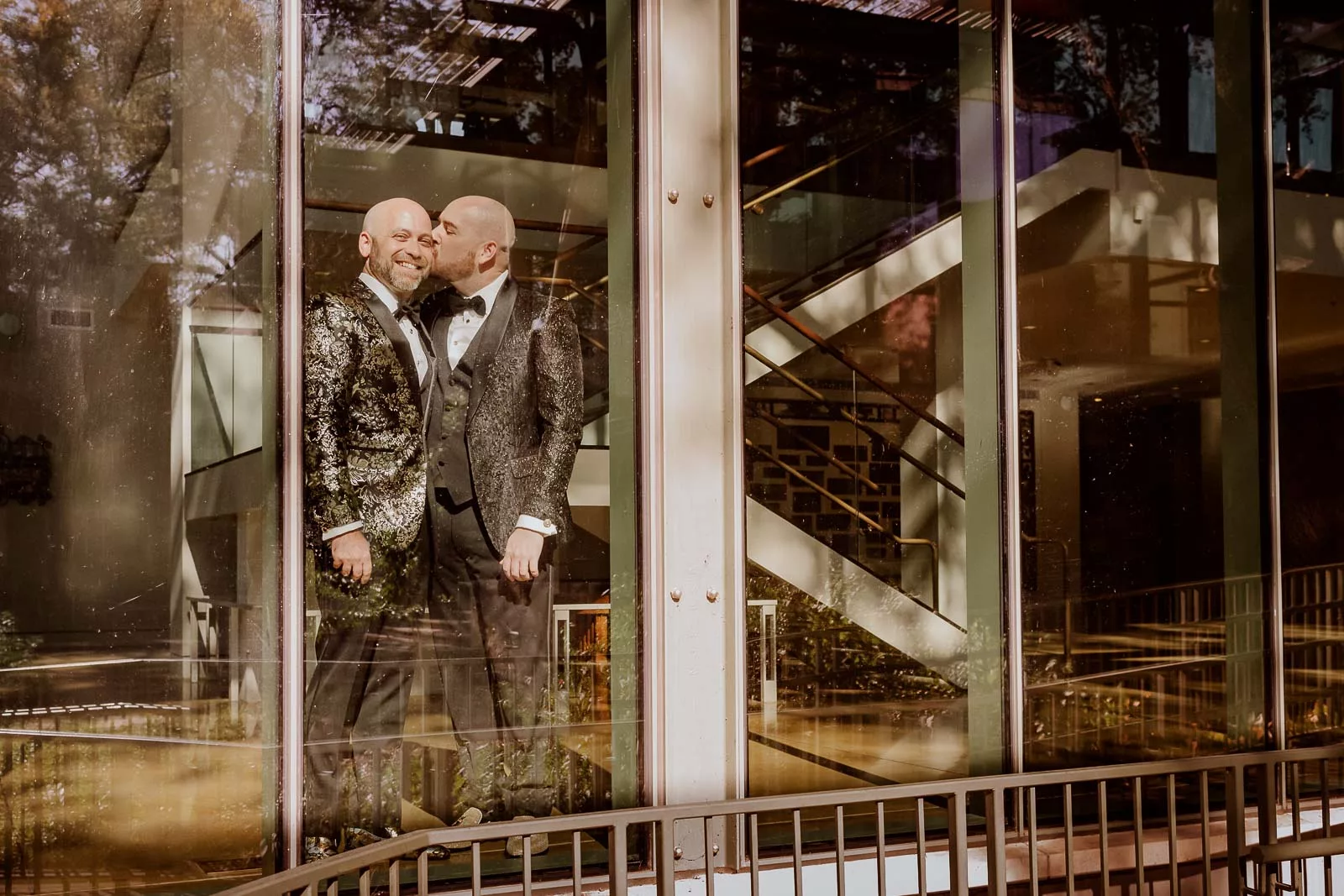 Couple Wayne and Derek hold hands inside window of the Witte Museum on wedding day