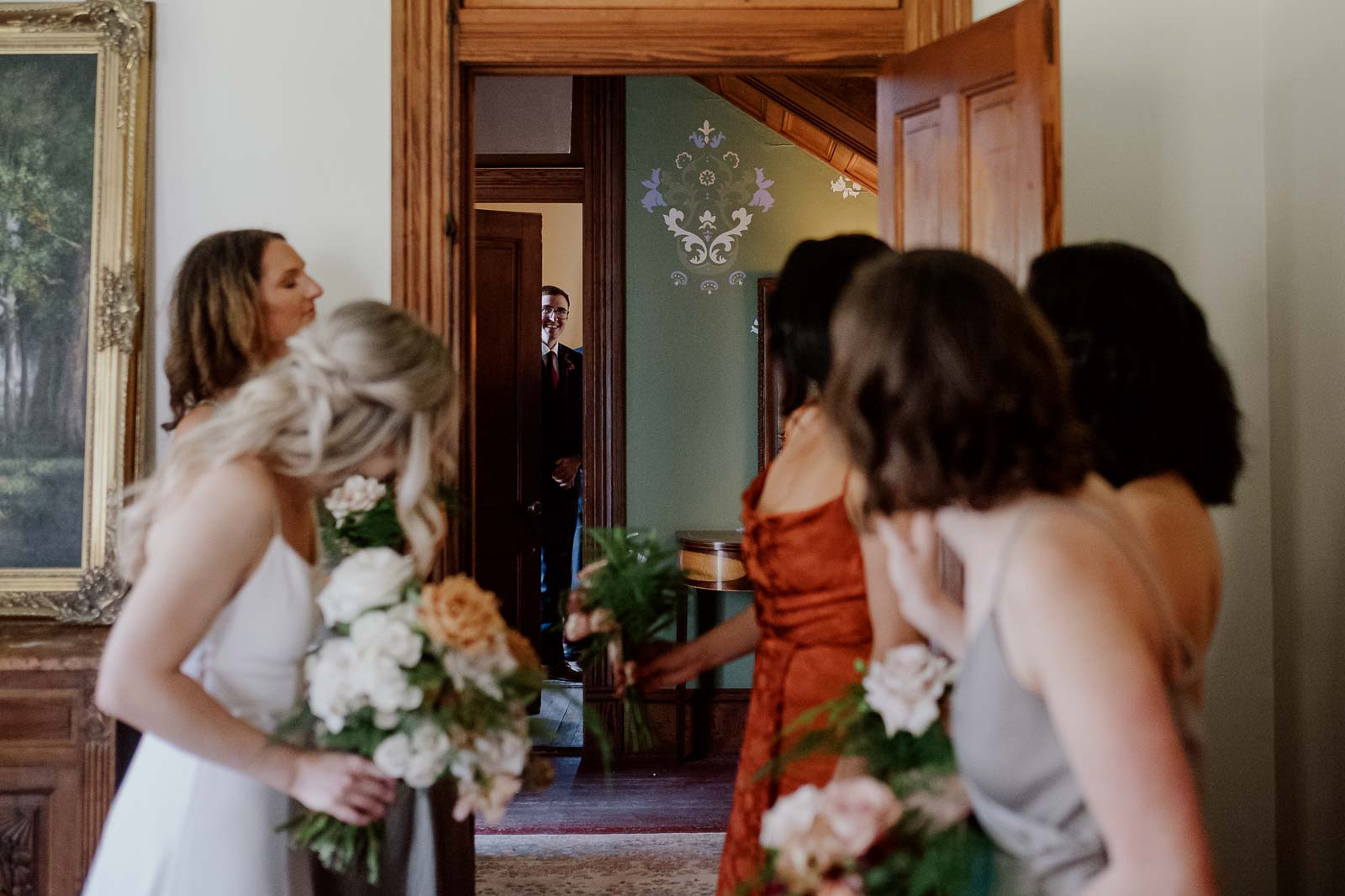 A groomsmen looks out from his room toward the bride and her party