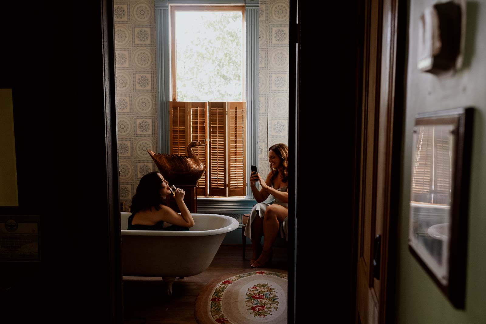 A bridesmaid sitting in the tub poses for an iPhone click