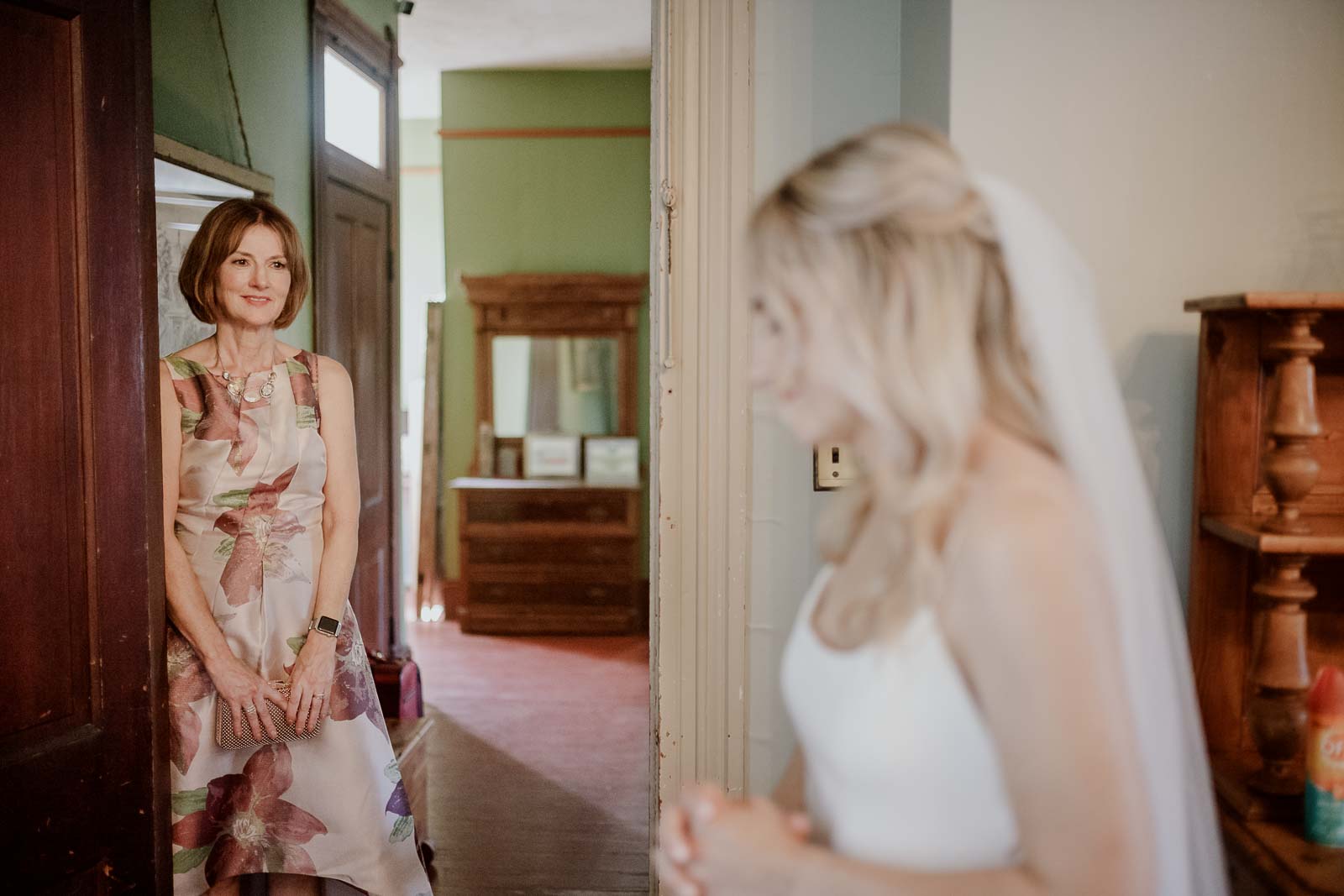 Mother of the bride looks adoringly at her daughter after fitting her veil