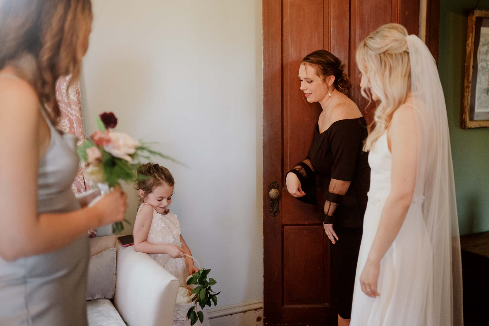 A cute flower girl acting shy in front of the bride and her mother