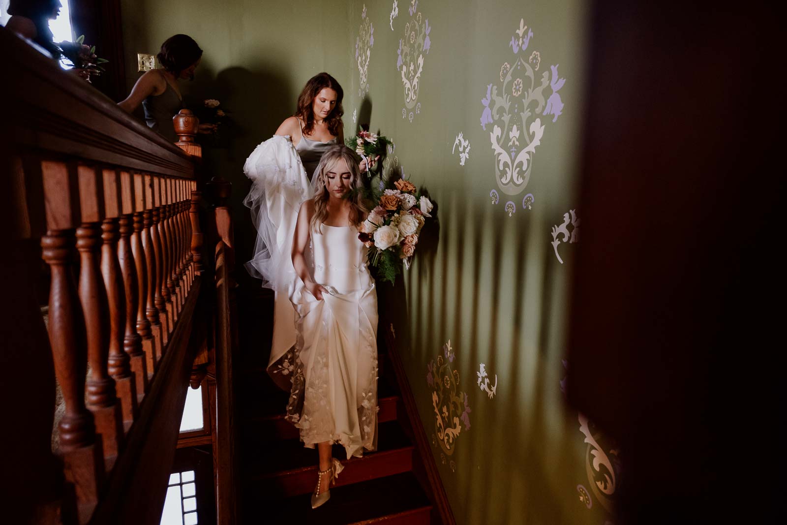 The bride leads the way down the old staircase at Barr Mansion