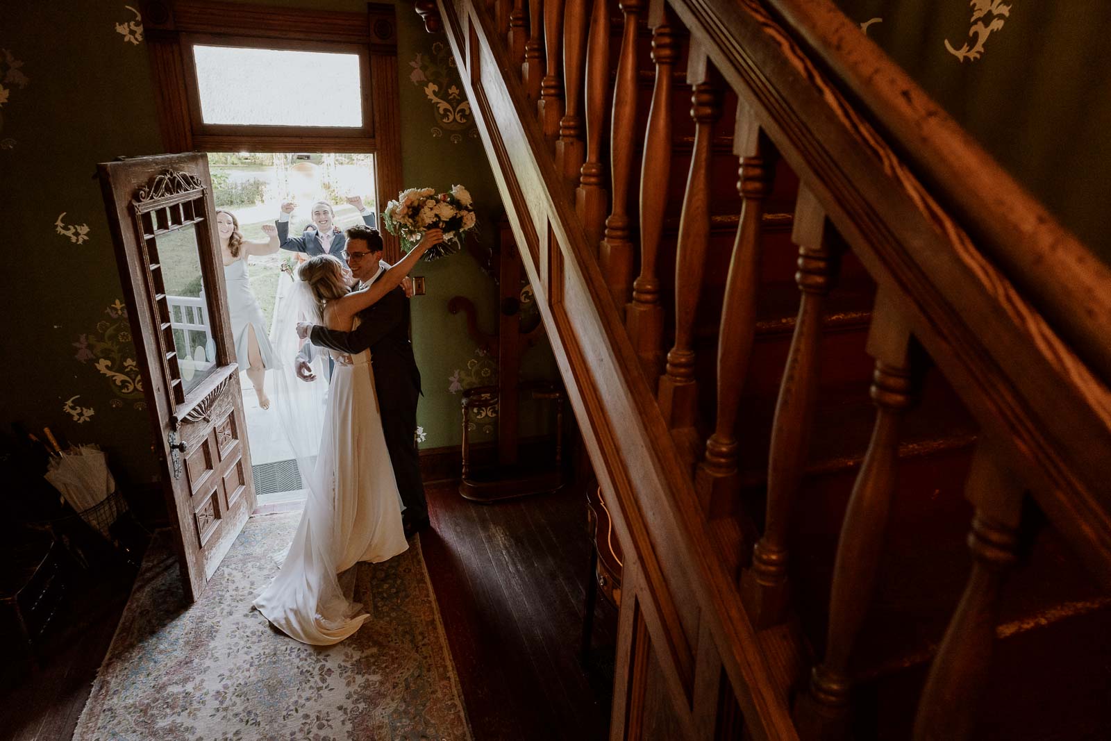 The last of three images in a series as the couple hug and kiss with the bridal party erupting in congratulations