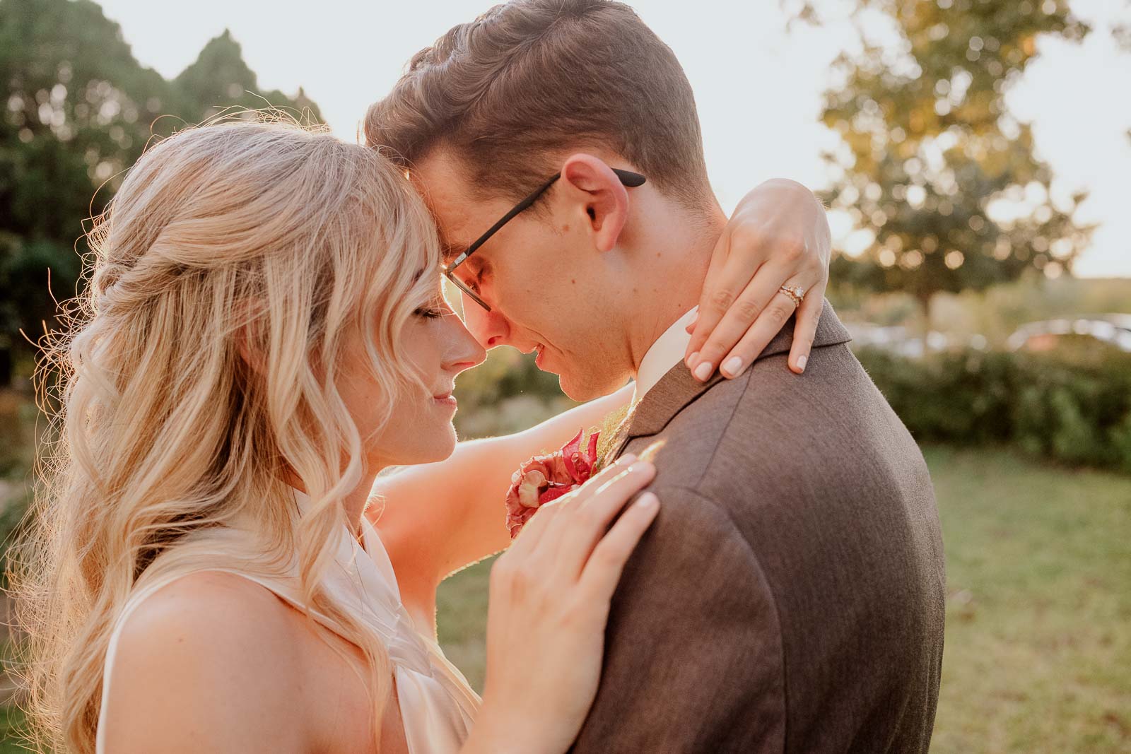 A couple are forehead to forehead with eyes closed at sunset